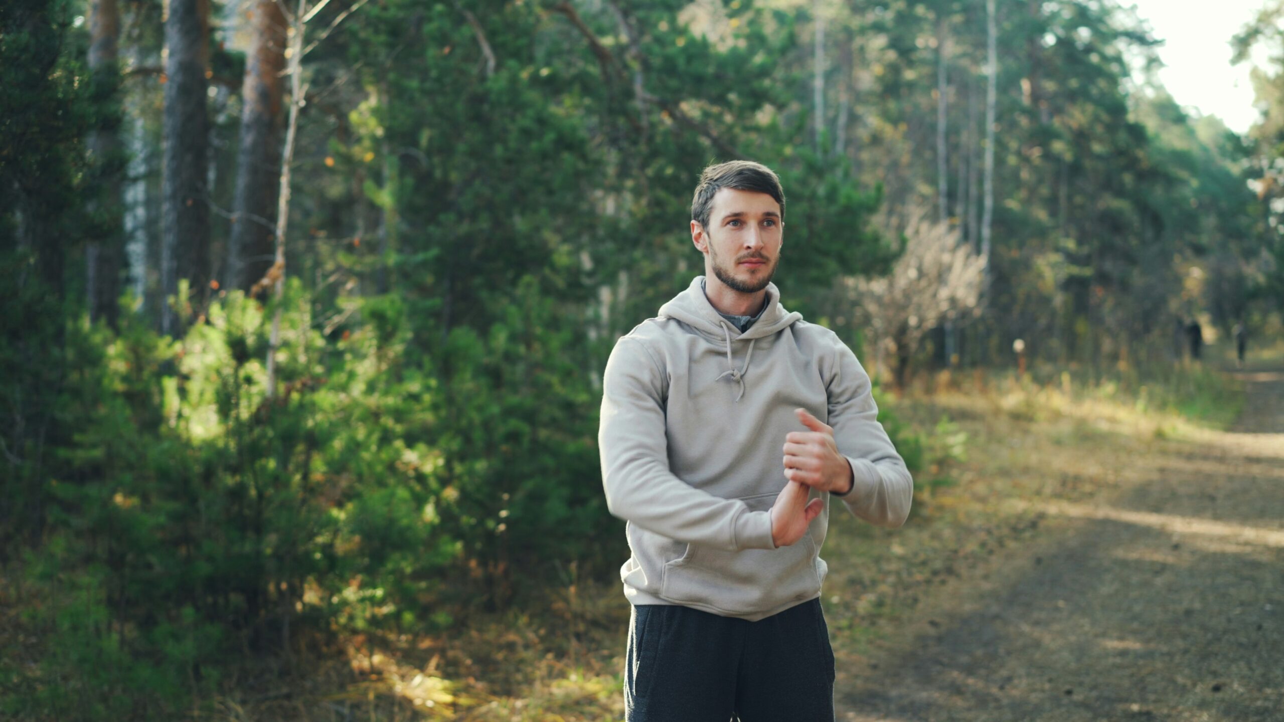 Uomo adulto attivo fa stretching all'aperto in un bosco dopo lo sport
