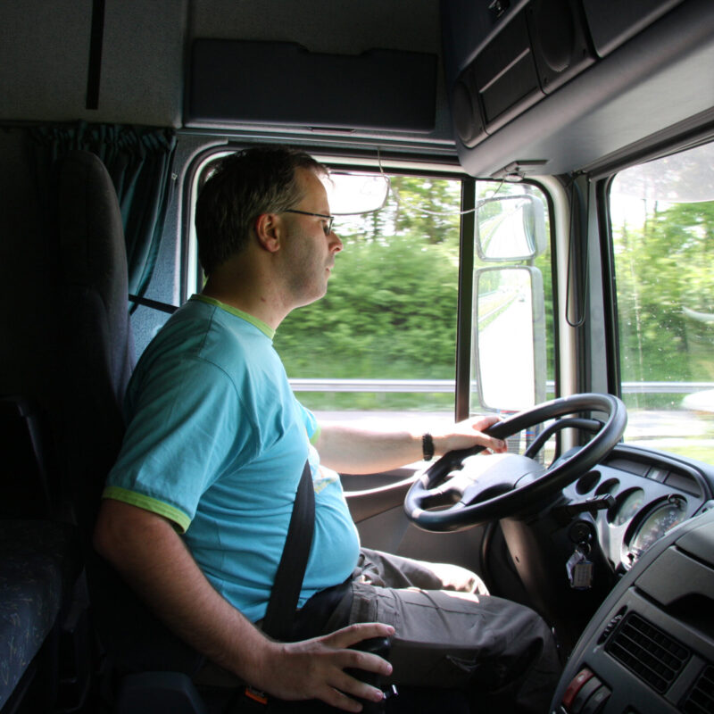 Autista di camion alla guida, seduto in cabina mentre osserva la strada