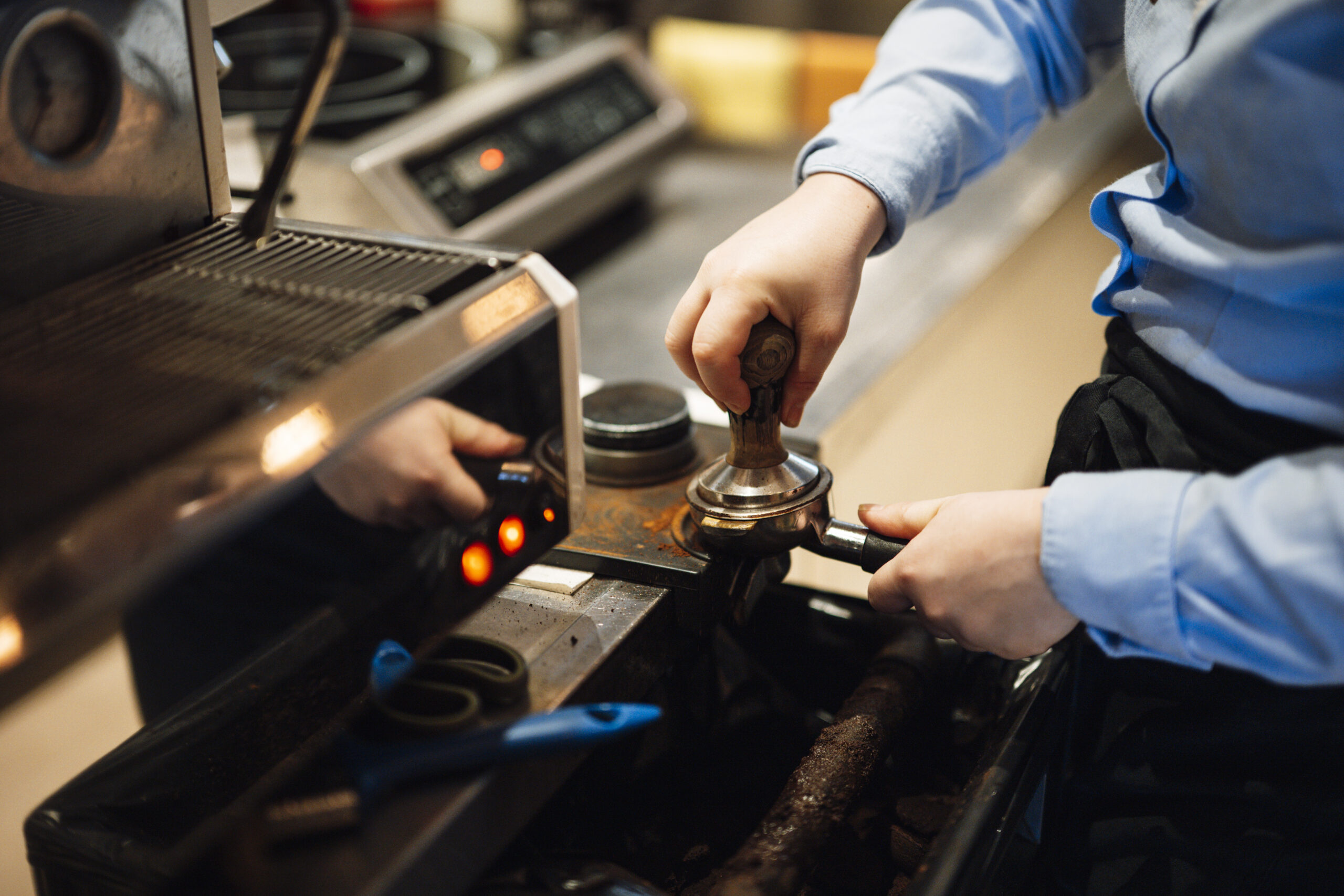 Mani di un barista che preparano un espresso con il pressino sul portafiltro