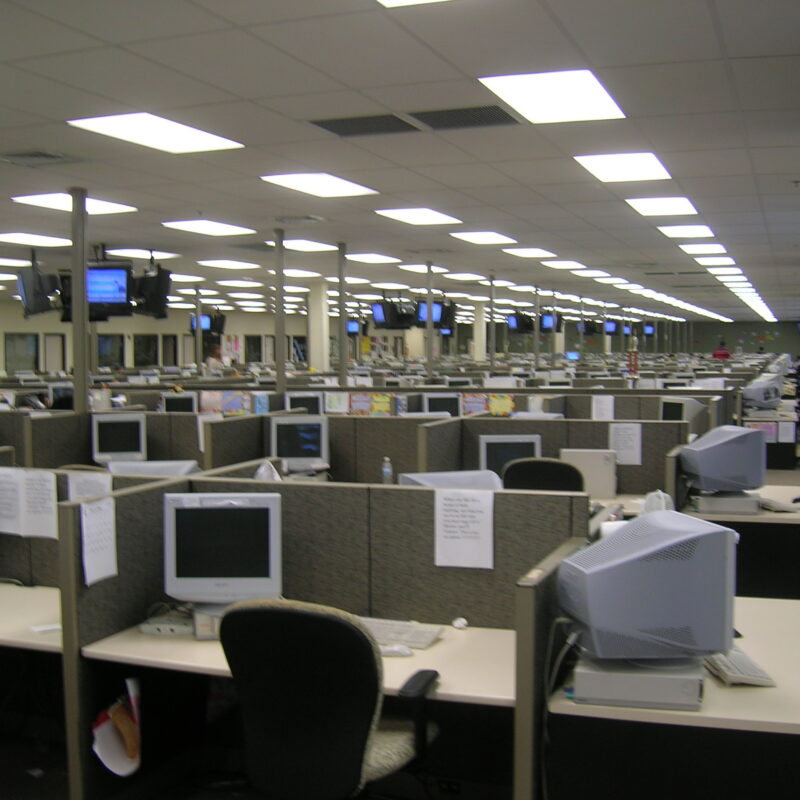 Postazioni di lavoro in un call center con cuffie e monitor, ambiente ufficio open space