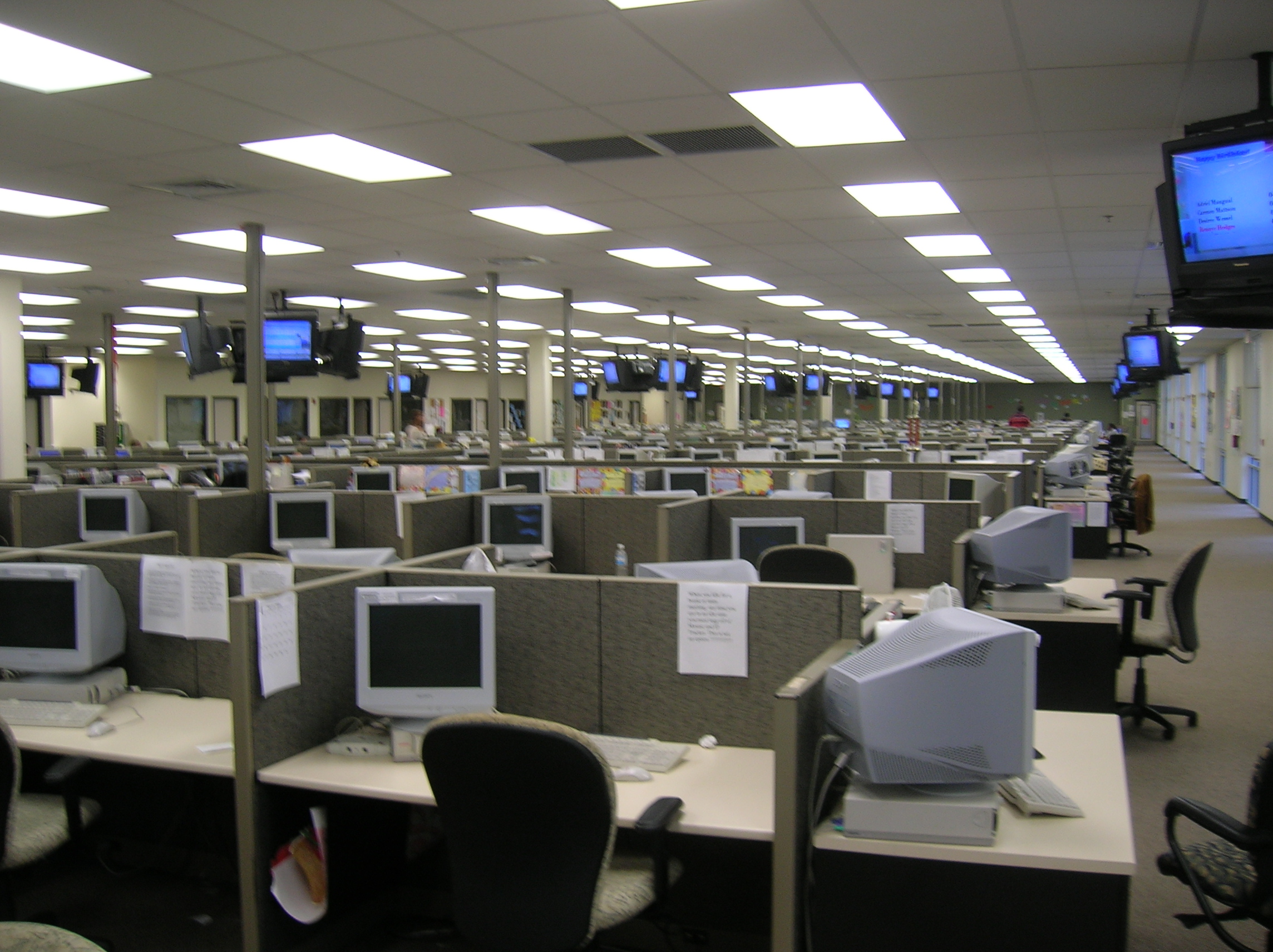 Postazioni di lavoro in un call center con cuffie e monitor, ambiente ufficio open space