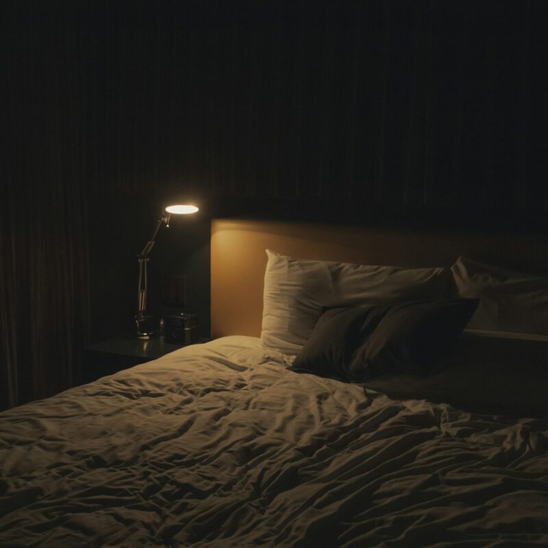 Camera da letto accogliente con lampada da comodino accesa, atmosfera rilassante per la sera
