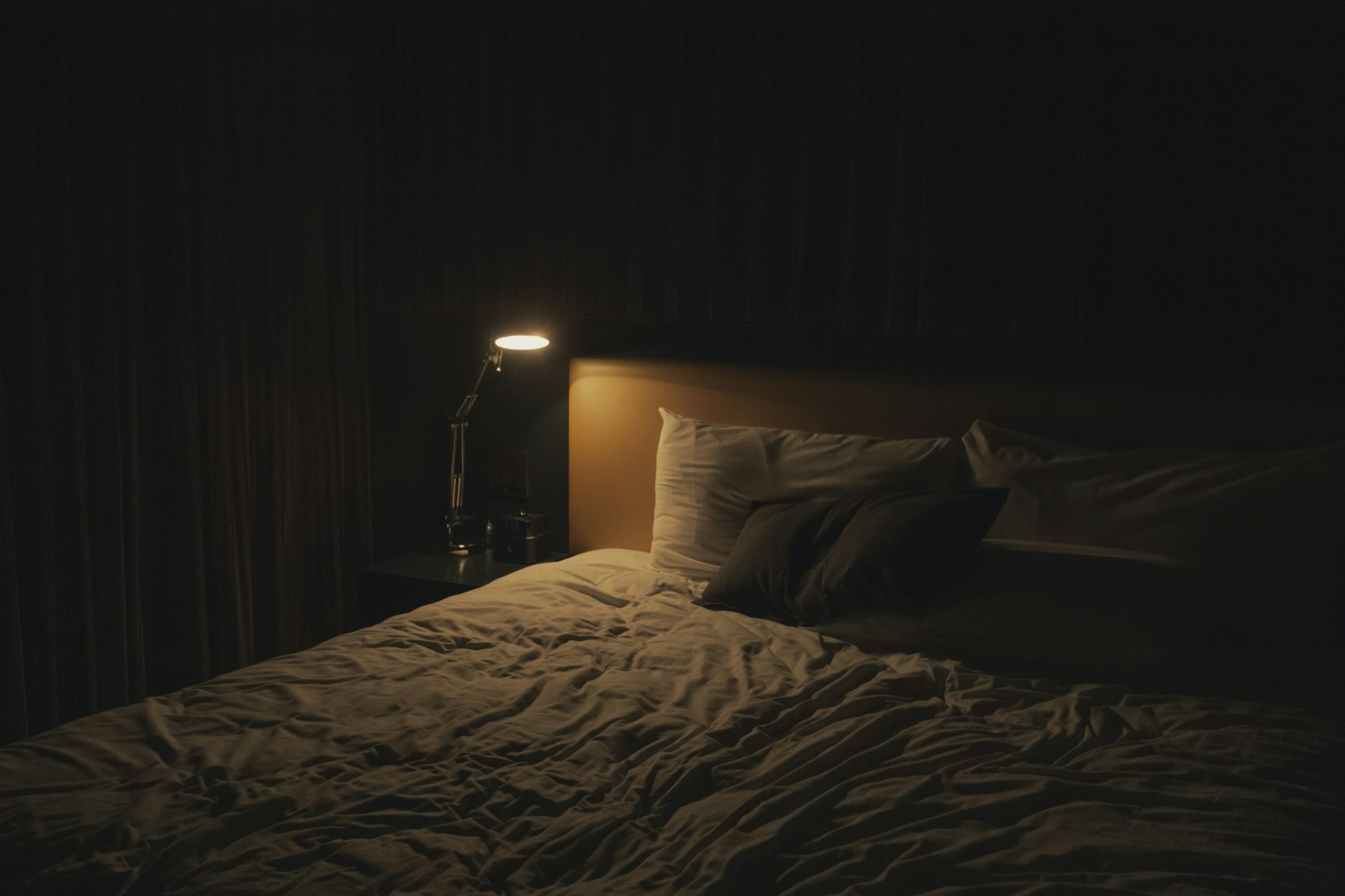 Camera da letto accogliente con lampada da comodino accesa, atmosfera rilassante per la sera