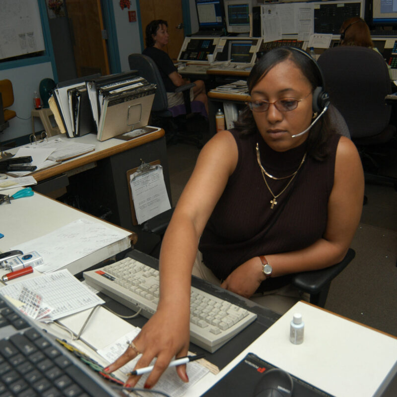 Operatrice di centrale operativa di emergenza al lavoro con cuffie e console radio