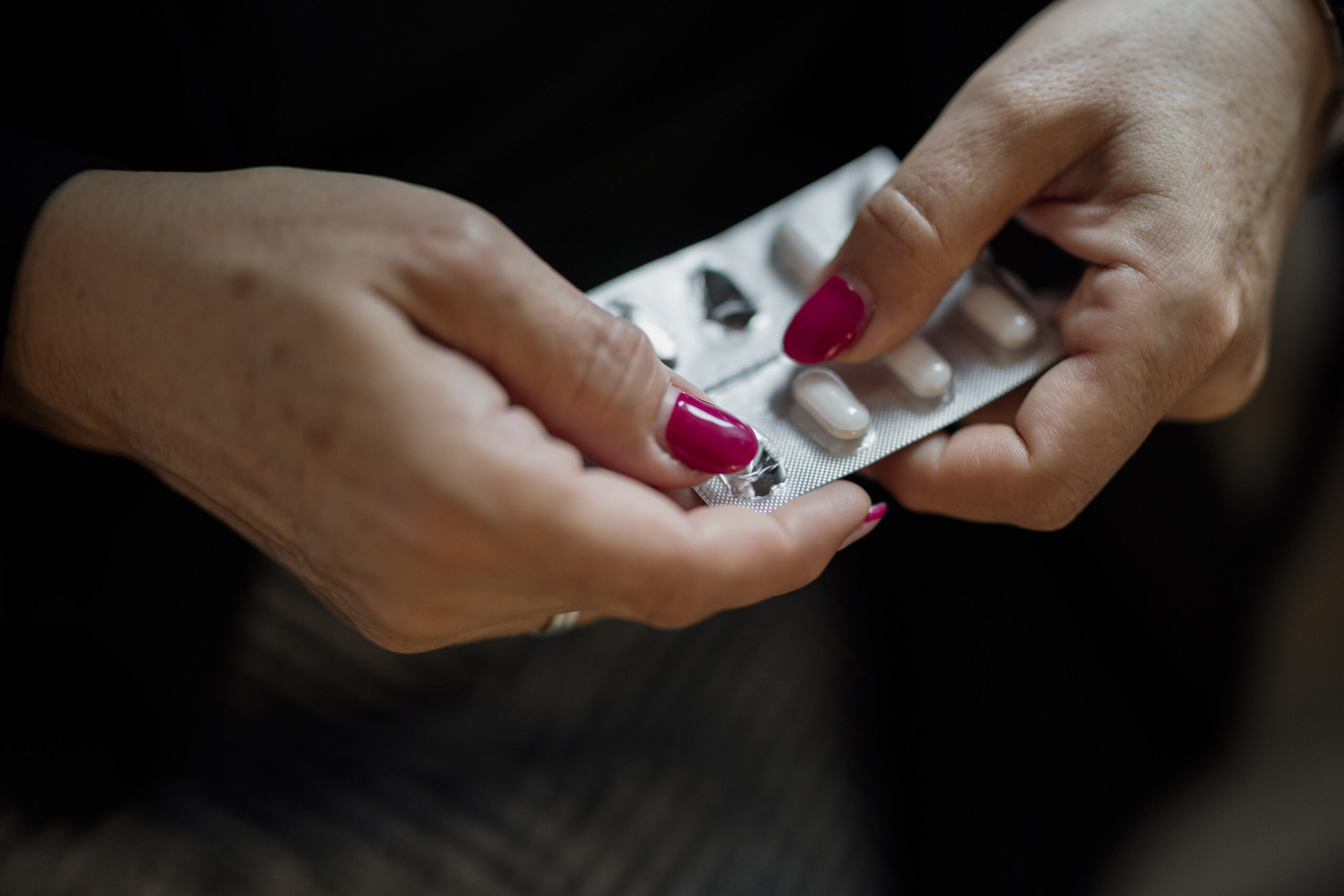 Mani che tengono una confezione di capsule prima dell'assunzione