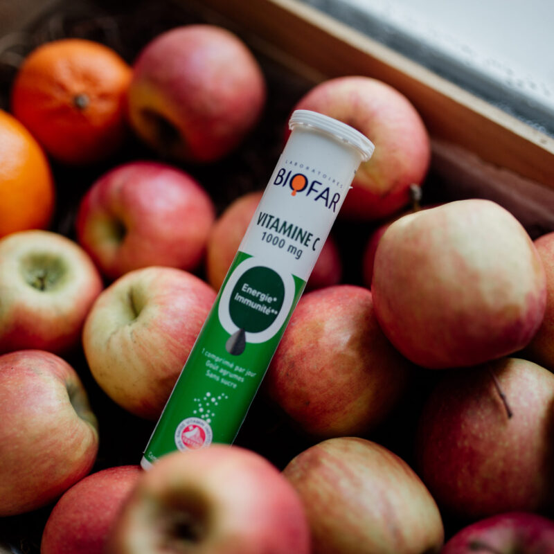Frutta fresca e integratore di vitamina C in un cesto di legno