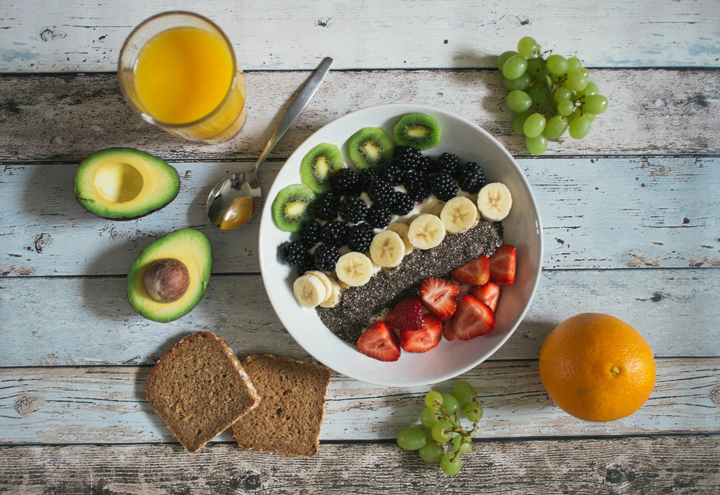 Tavola con colazione sana, frutta fresca e succo d'arancia