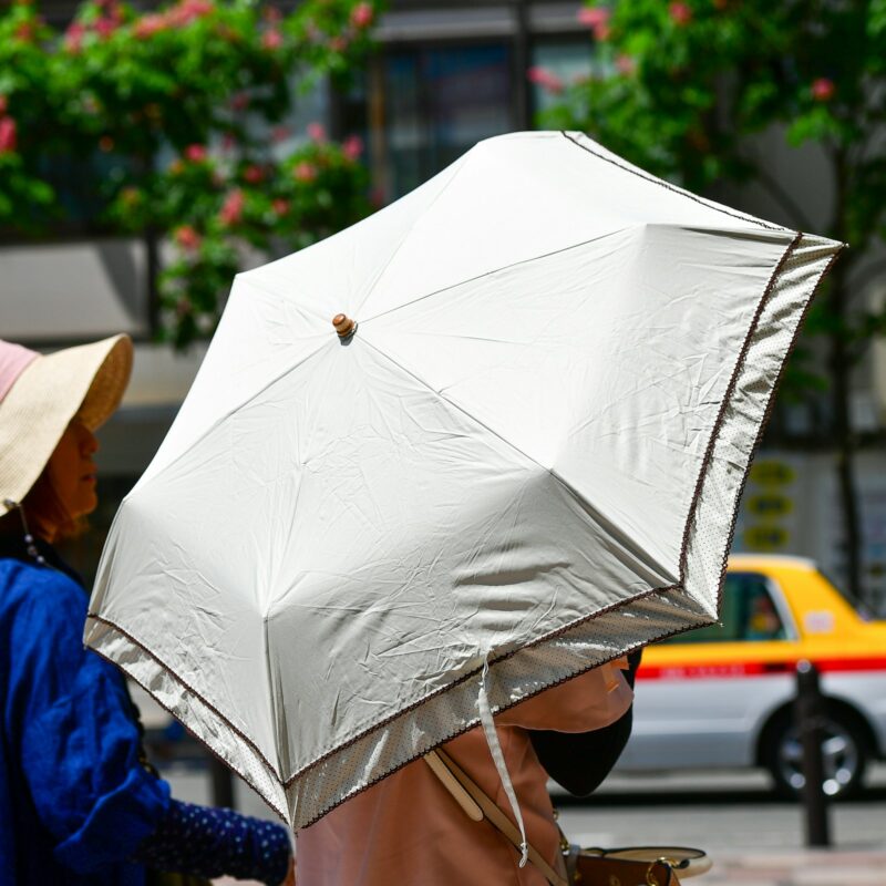 Persone che camminano protette dal sole con un parasole in una giornata calda