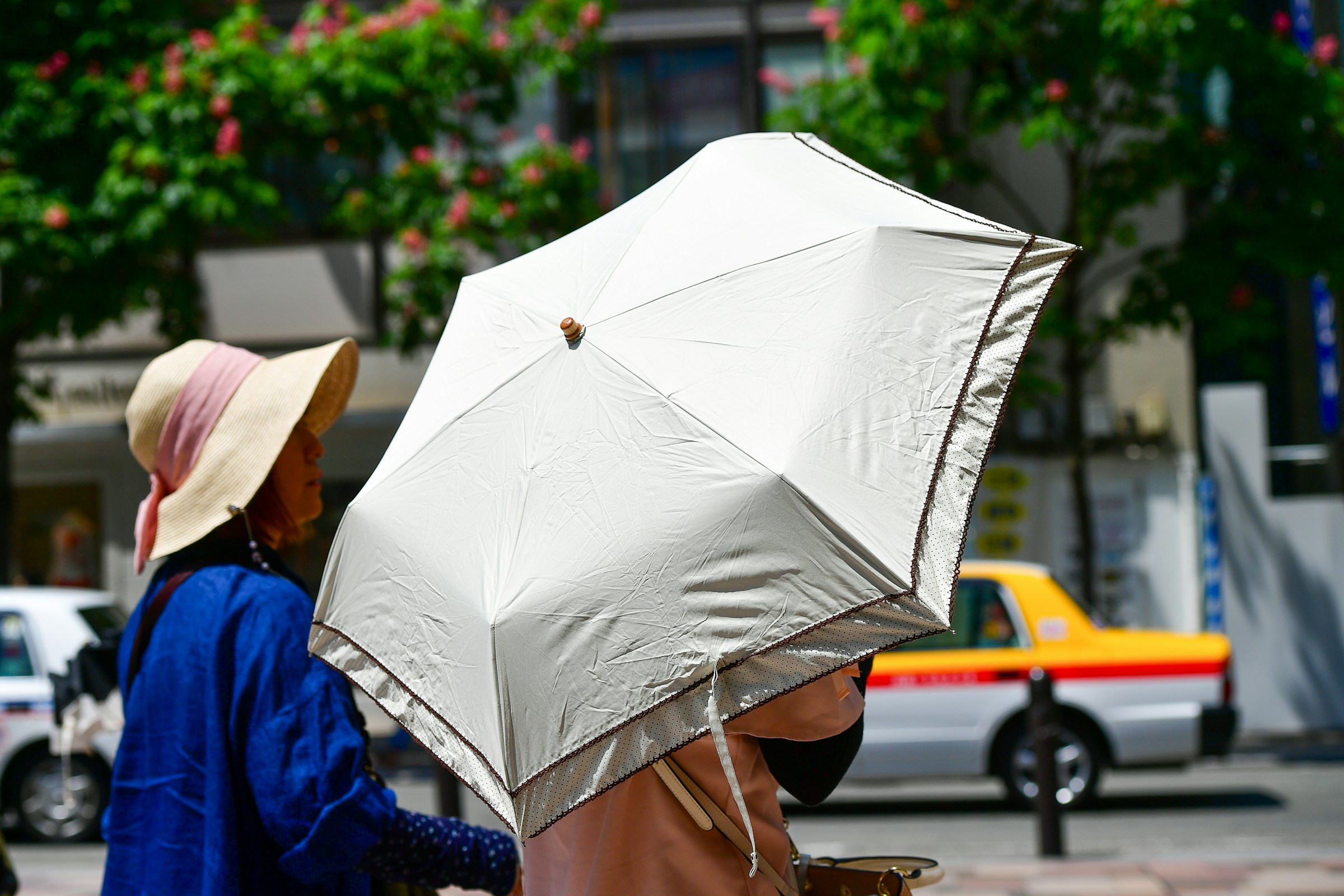 Persone che camminano protette dal sole con un parasole in una giornata calda