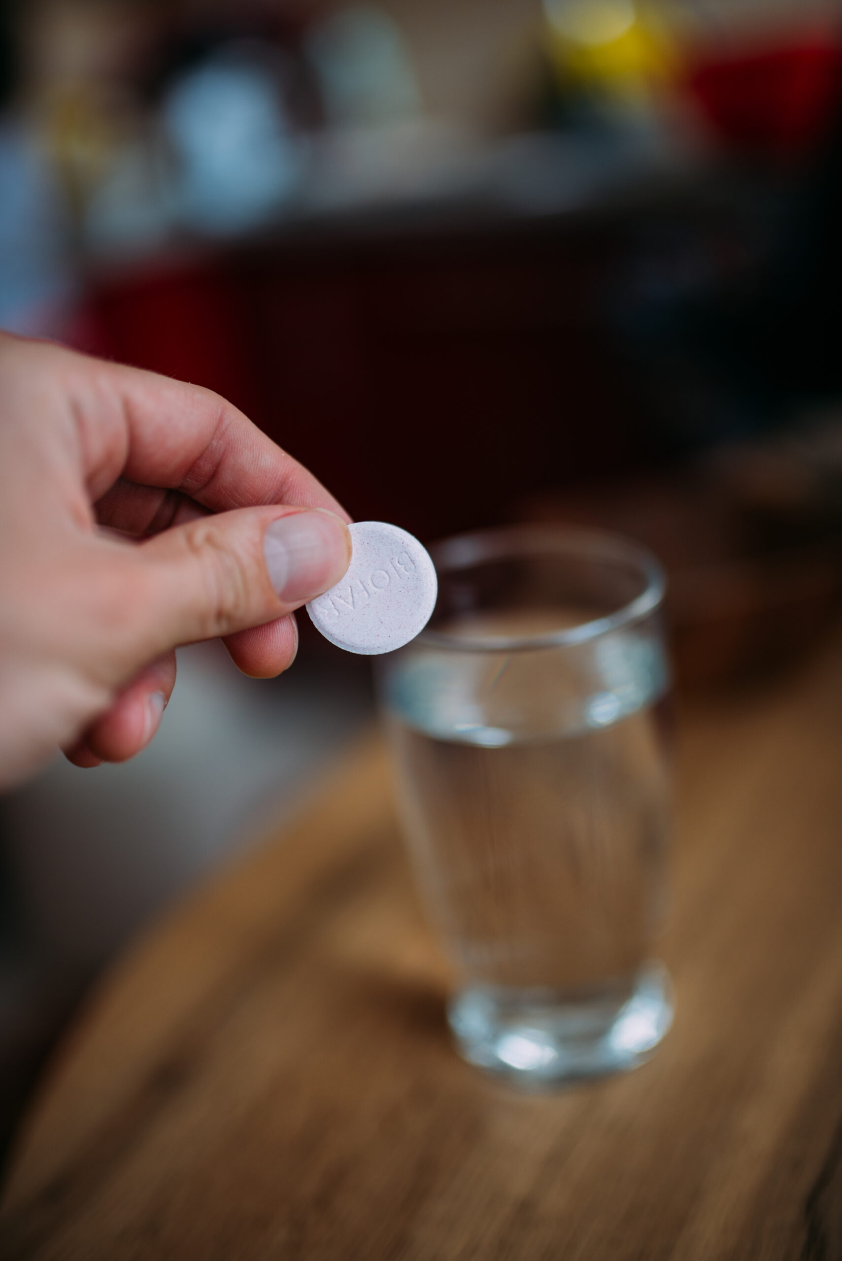 Persona tiene una compressa effervescente sopra un bicchiere d'acqua