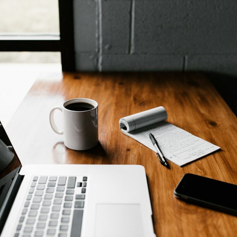 Scrivania da lavoro con laptop, tazza di caffè e taccuino, atmosfera di concentrazione