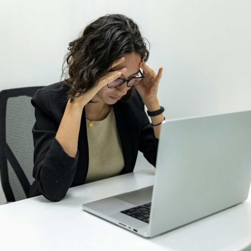Donna stanca davanti al computer si massaggia la testa