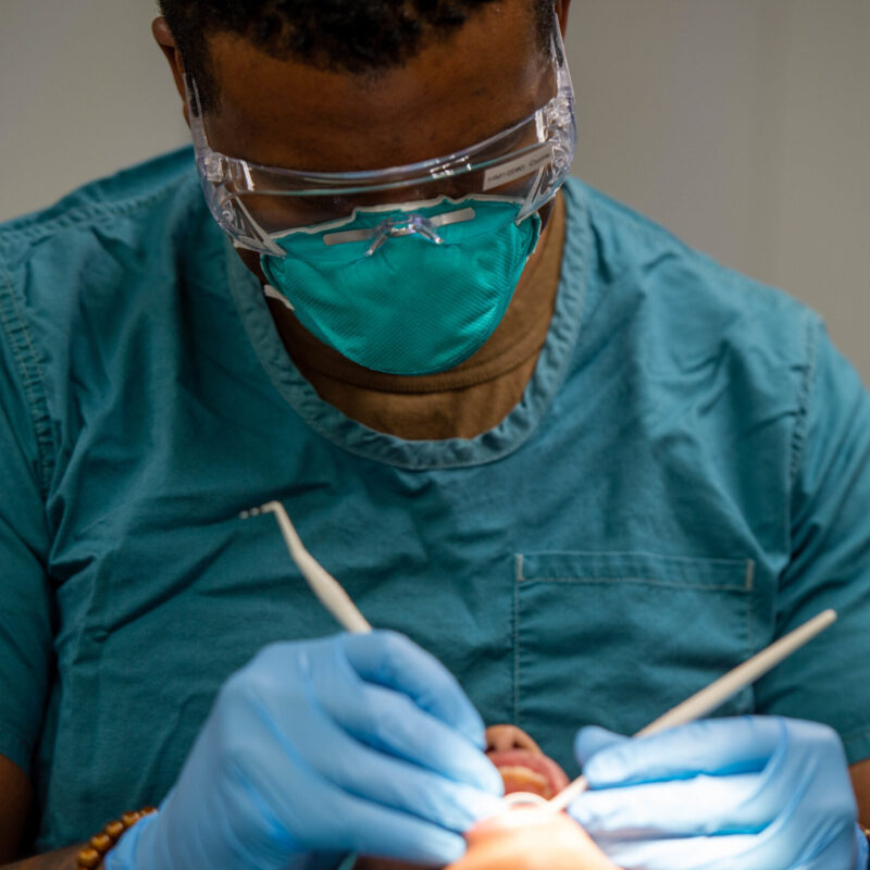 Dentista con mascherina e occhiali protettivi al lavoro con strumenti odontoiatrici