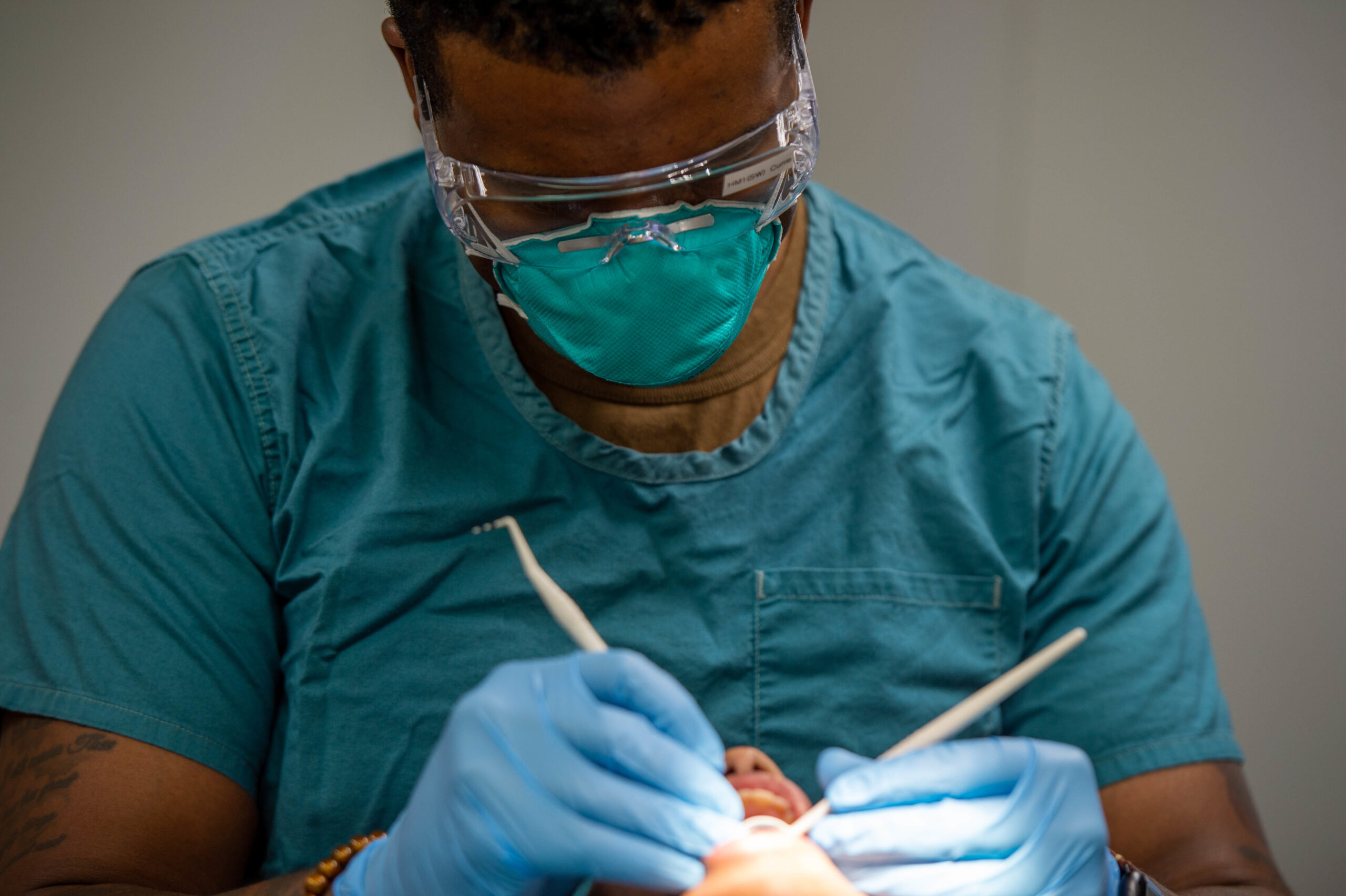 Dentista con mascherina e occhiali protettivi al lavoro con strumenti odontoiatrici