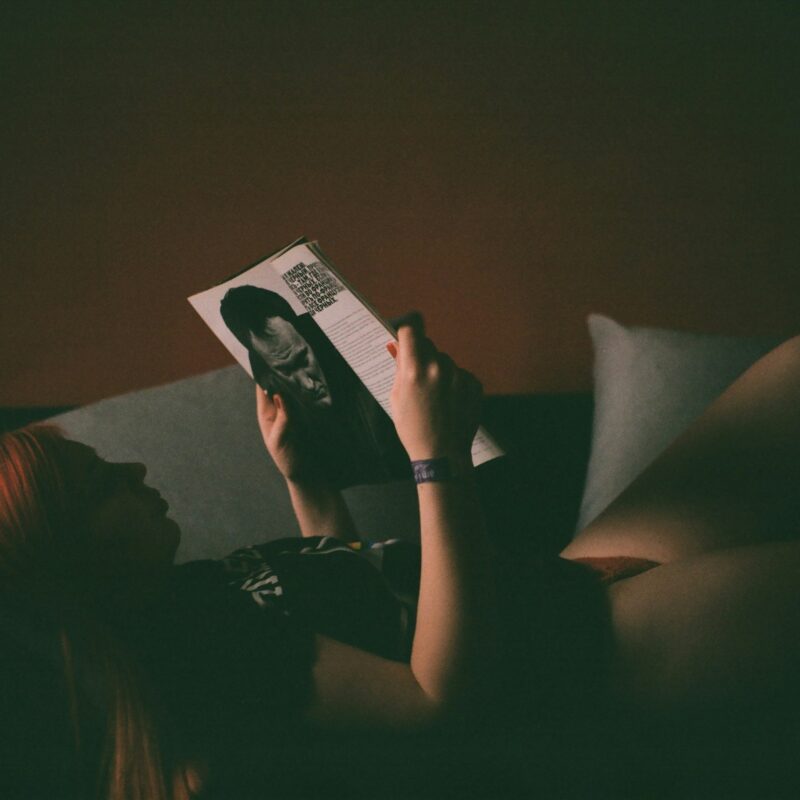 Donna rilassata sul divano che legge una rivista invece di usare lo smartphone