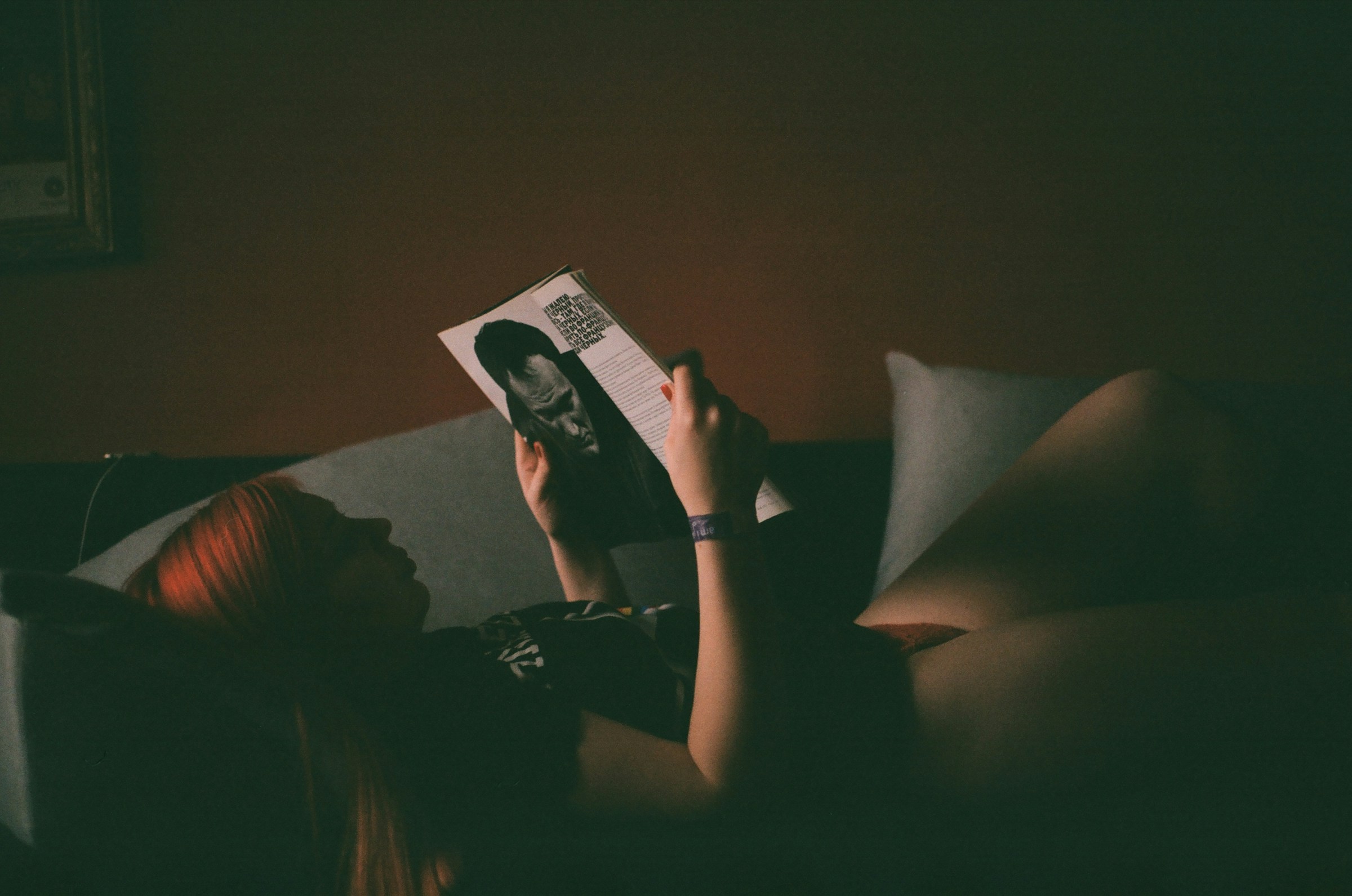 Donna rilassata sul divano che legge una rivista invece di usare lo smartphone