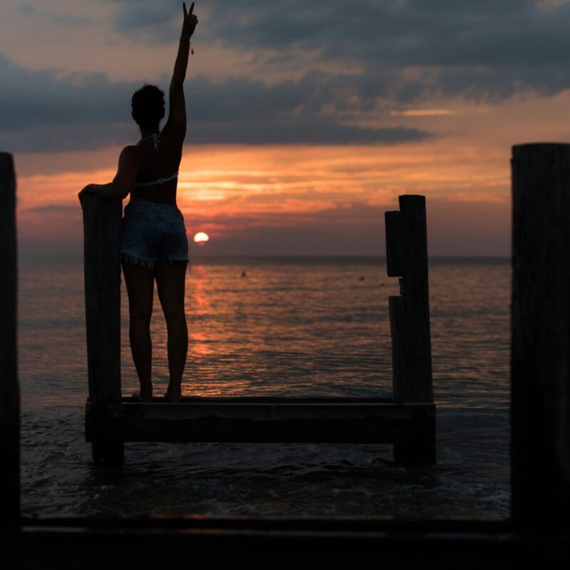 Donna in piedi durante l'alba, braccio alzato, momento di energia mattutina