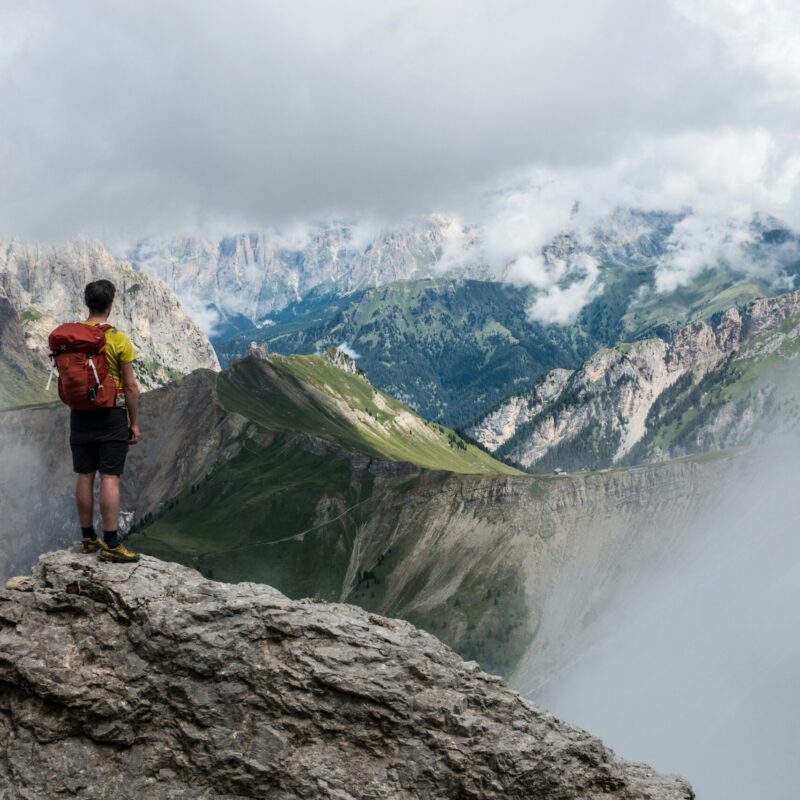 Escursionista con zaino osserva il panorama di montagna durante un trekking in alta quota