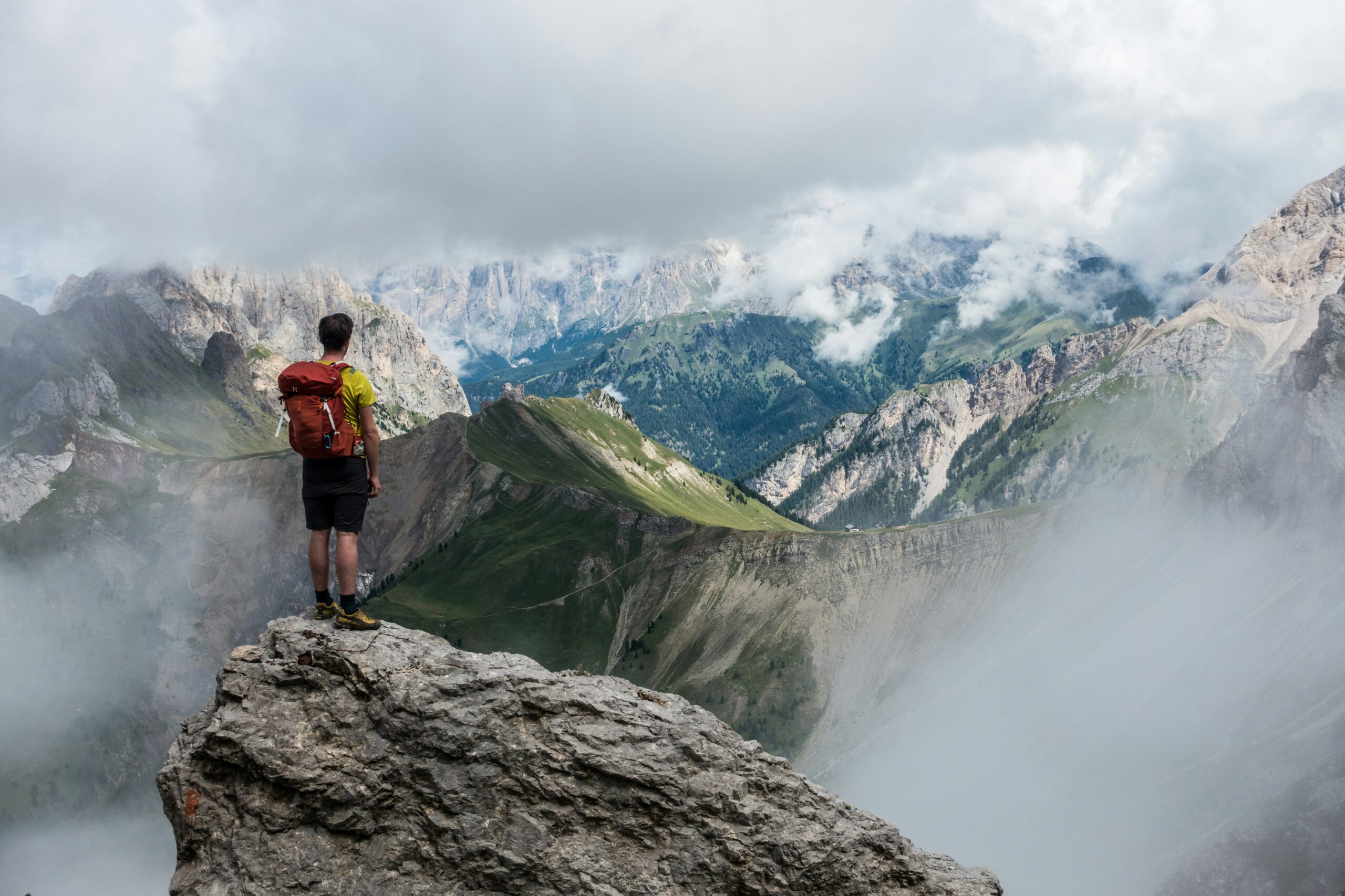 Escursionista con zaino osserva il panorama di montagna durante un trekking in alta quota
