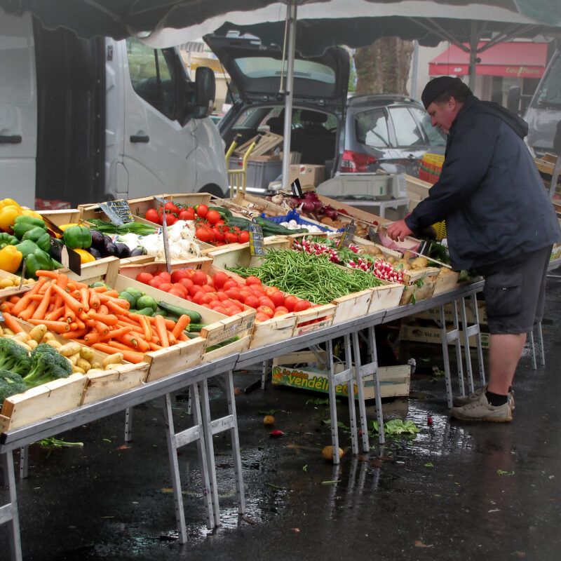 Fruttivendolo sistema la frutta e verdura sulla bancarella al mercato