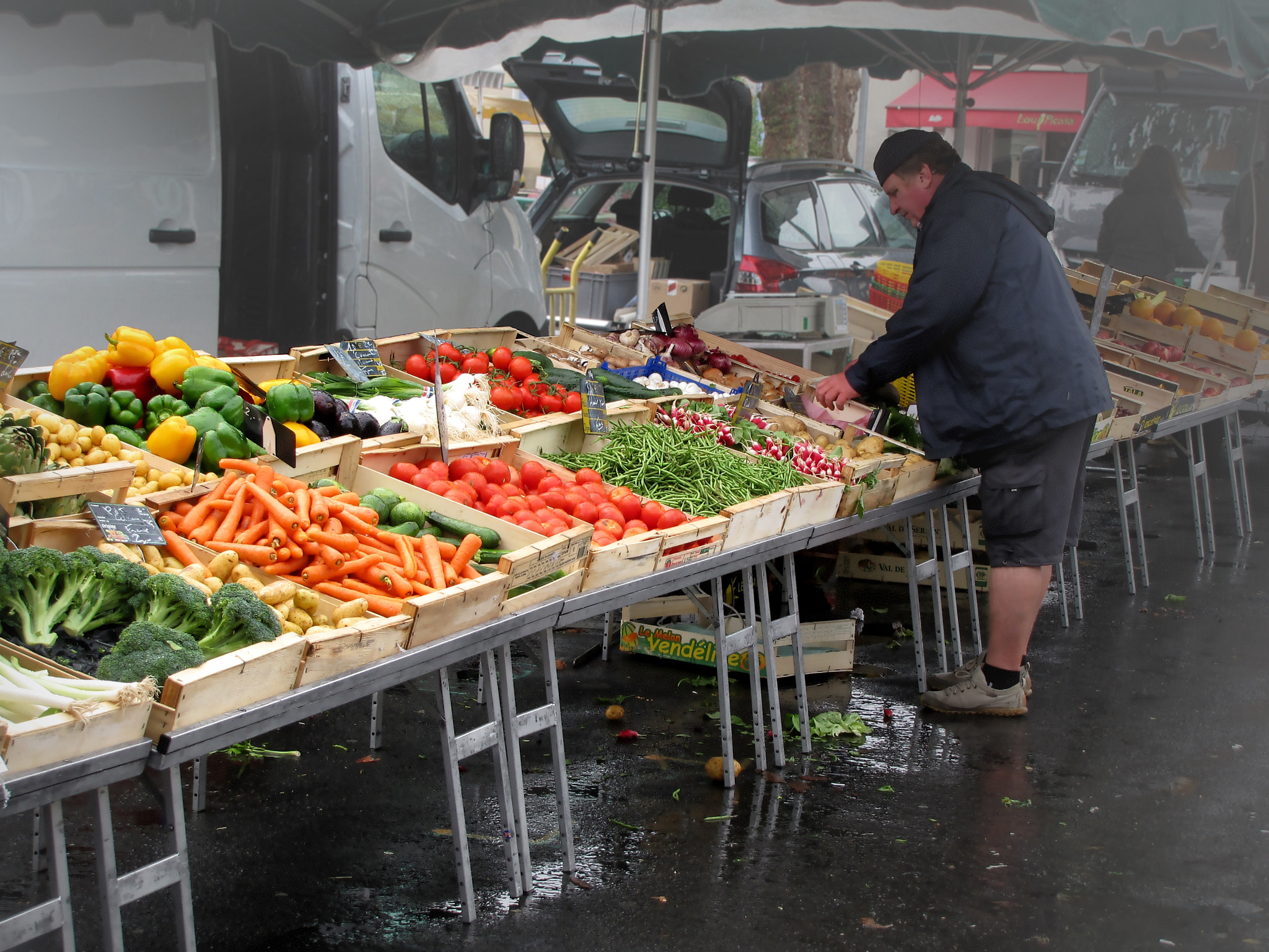 Fruttivendolo sistema la frutta e verdura sulla bancarella al mercato