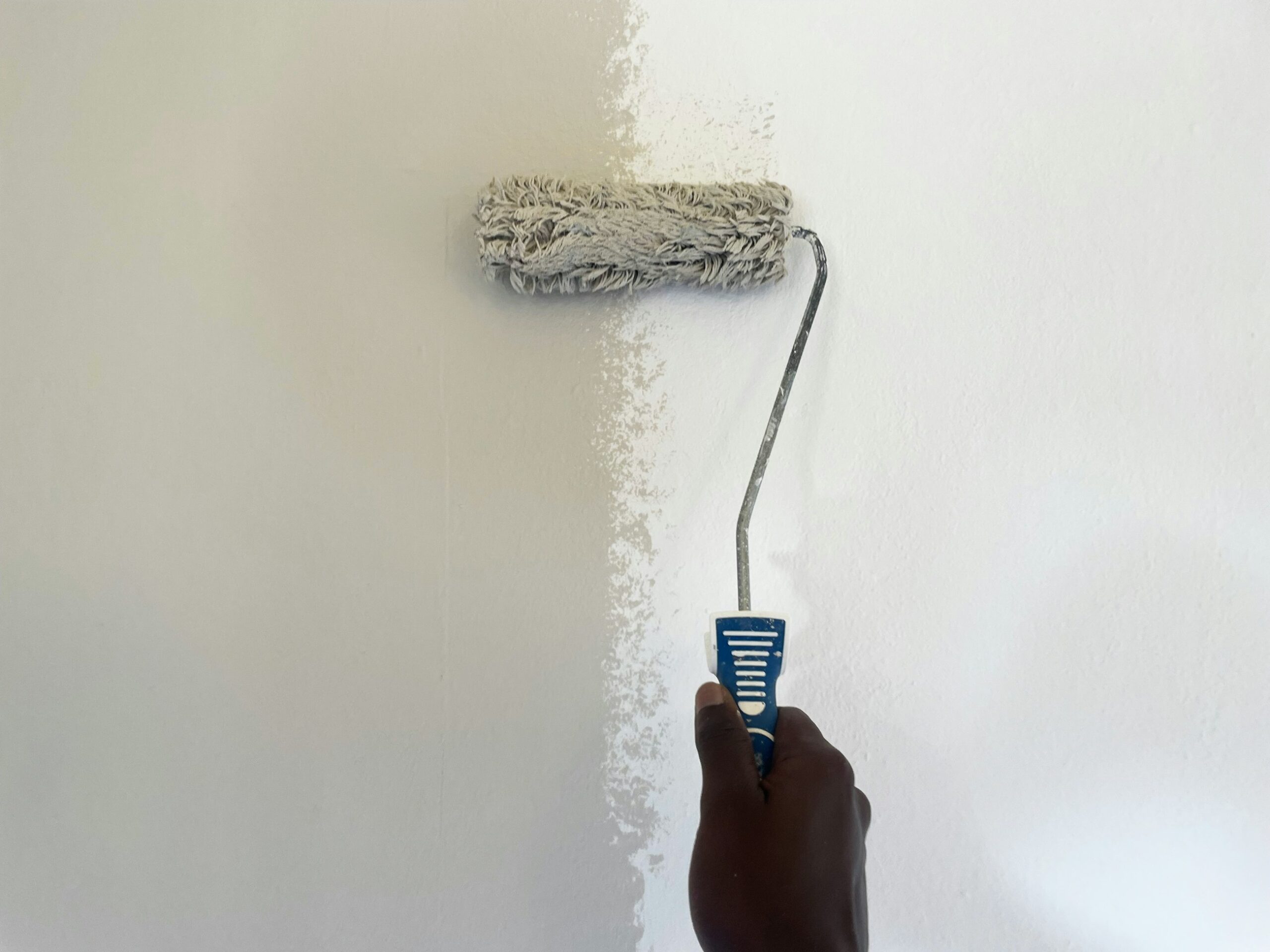 Persona che imbianca una parete con un rullo da pittura