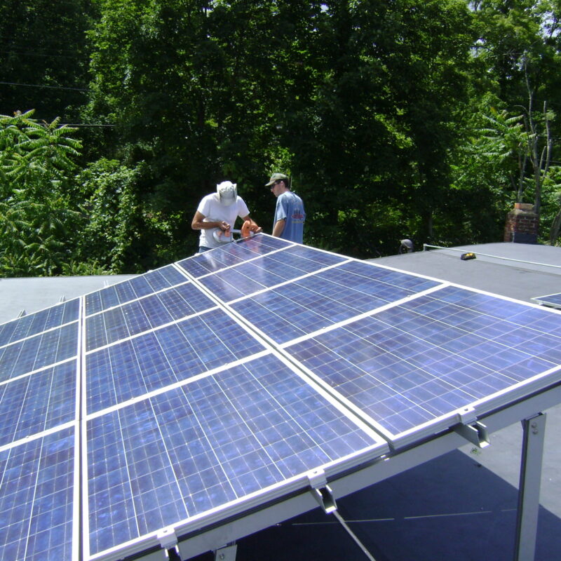 Due installatori montano un impianto fotovoltaico su un tetto, pannelli solari inclinati al sole