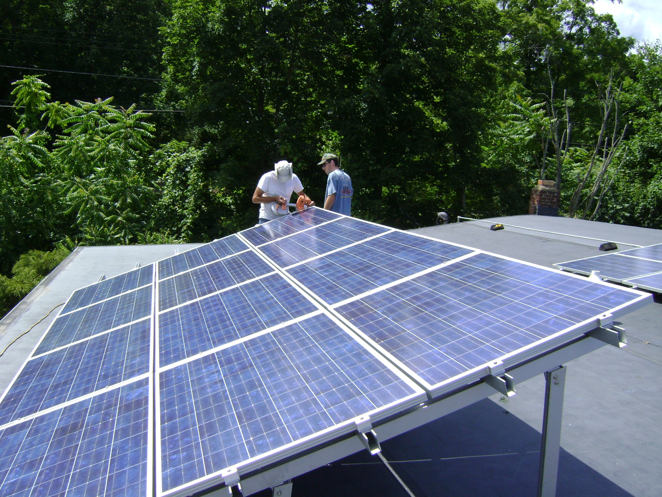 Due installatori montano un impianto fotovoltaico su un tetto, pannelli solari inclinati al sole