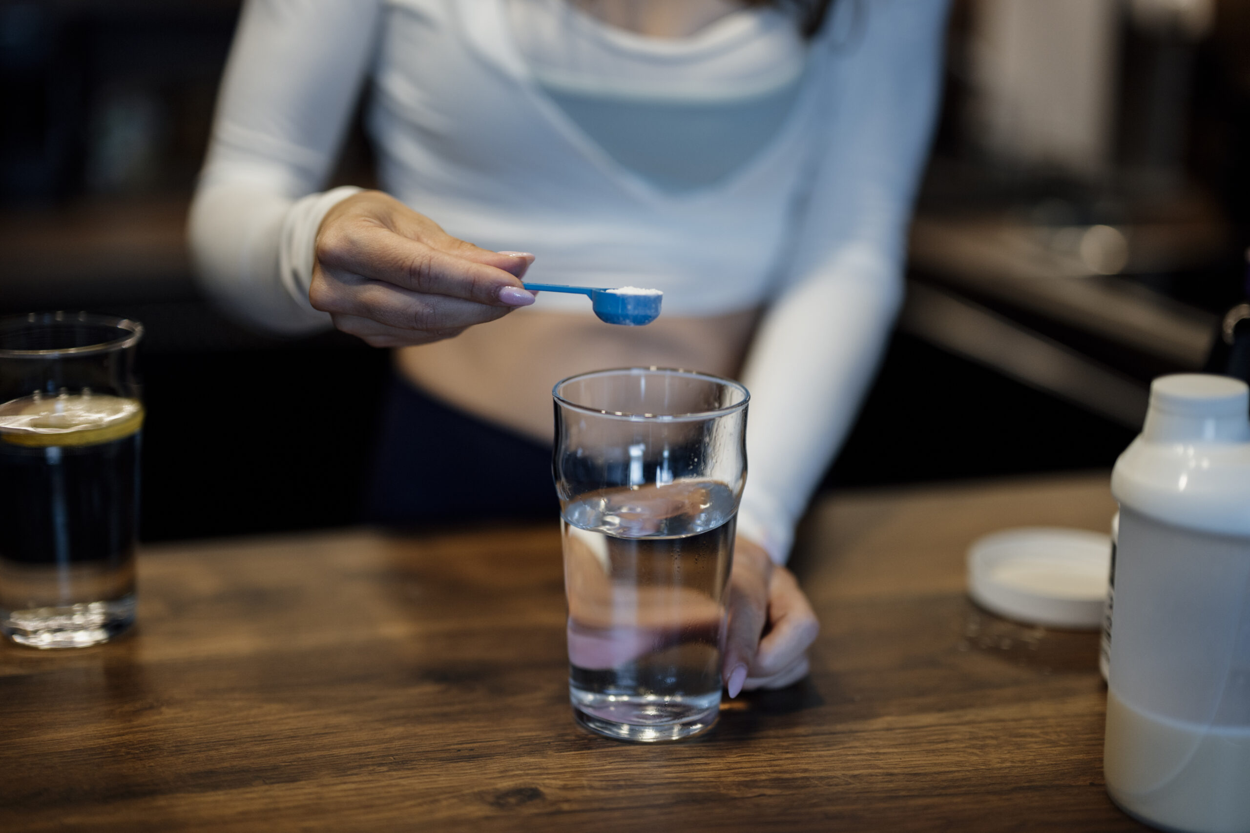 Persona scioglie una polvere in un bicchiere d'acqua in cucina
