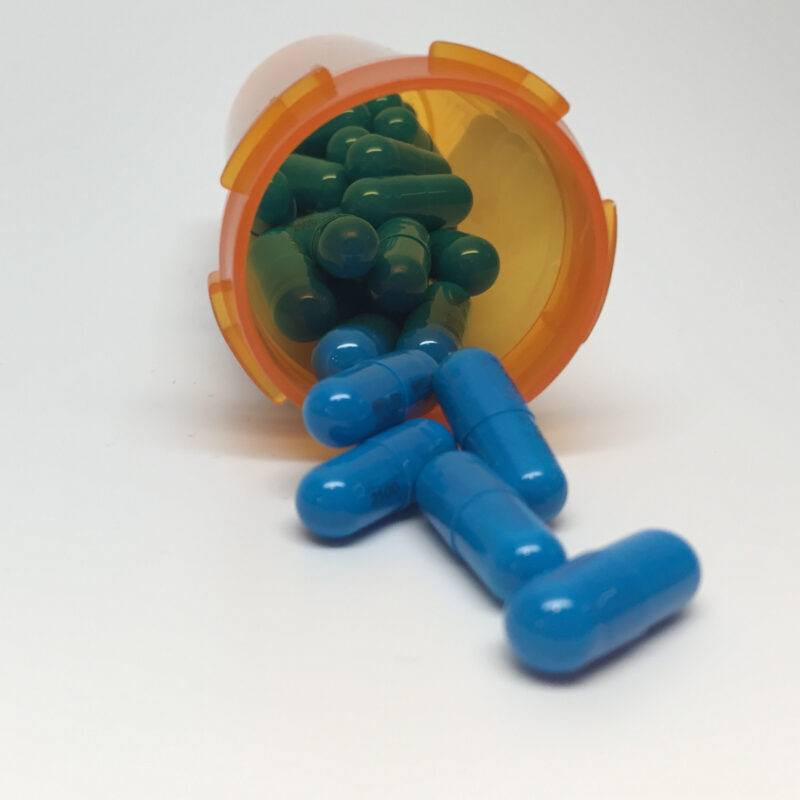 Capsule di integratore che fuoriescono da un flacone, con etichetta e numero di lotto