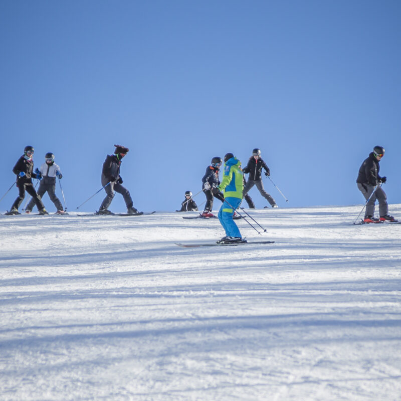 Maestro di sci che insegna a un gruppo su una pista innevata
