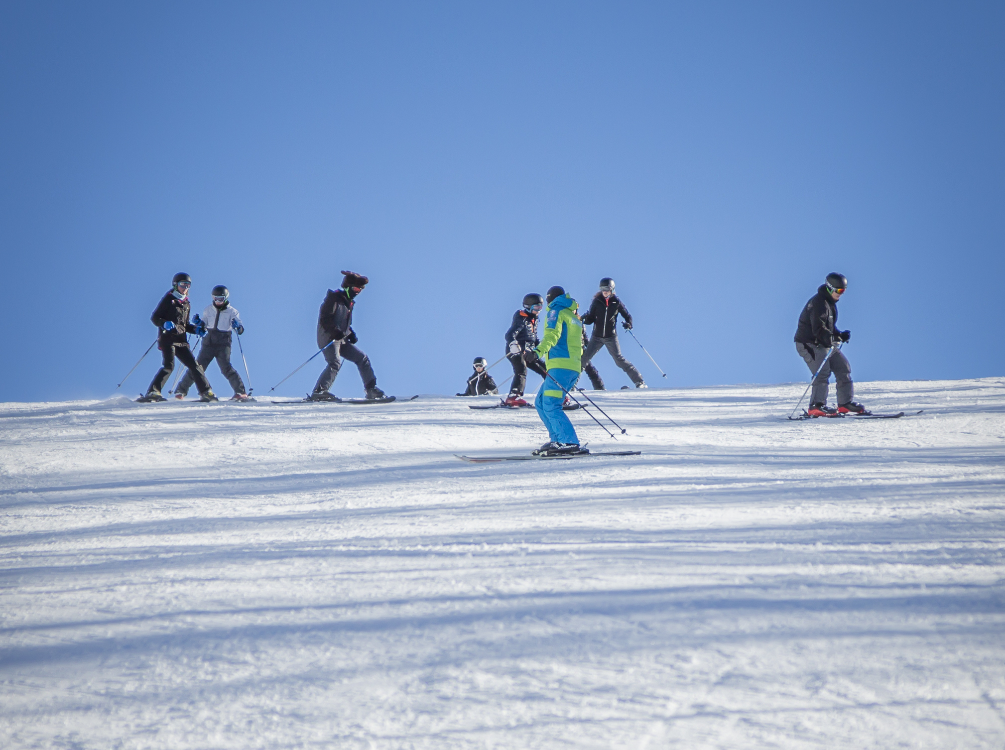 Maestro di sci che insegna a un gruppo su una pista innevata