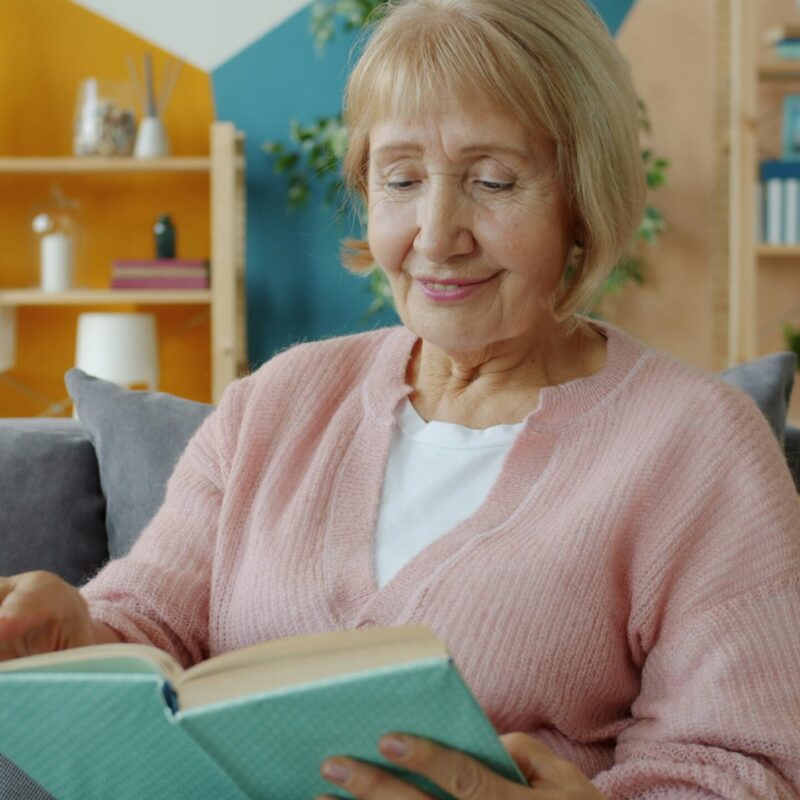 Donna anziana concentrata nella lettura di un libro, momento di attività mentale