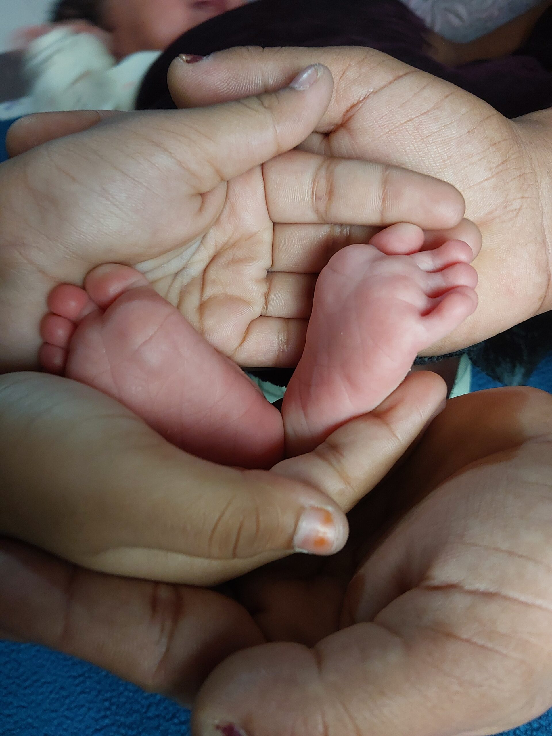 Piedini di un neonato tenuti dai familiari