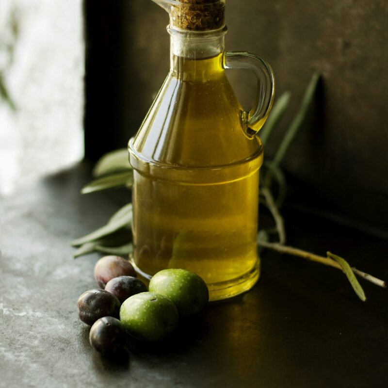 Bottiglia di olio extravergine di oliva e olive fresche, fonte di grassi buoni