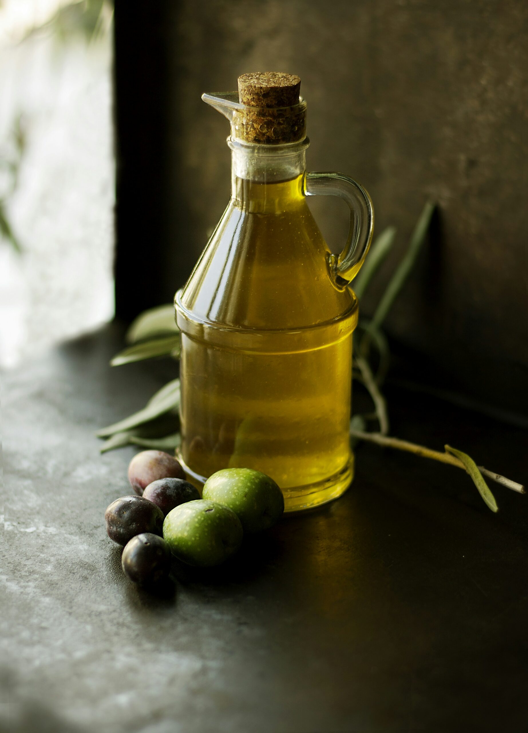 Bottiglia di olio extravergine di oliva e olive fresche, fonte di grassi buoni