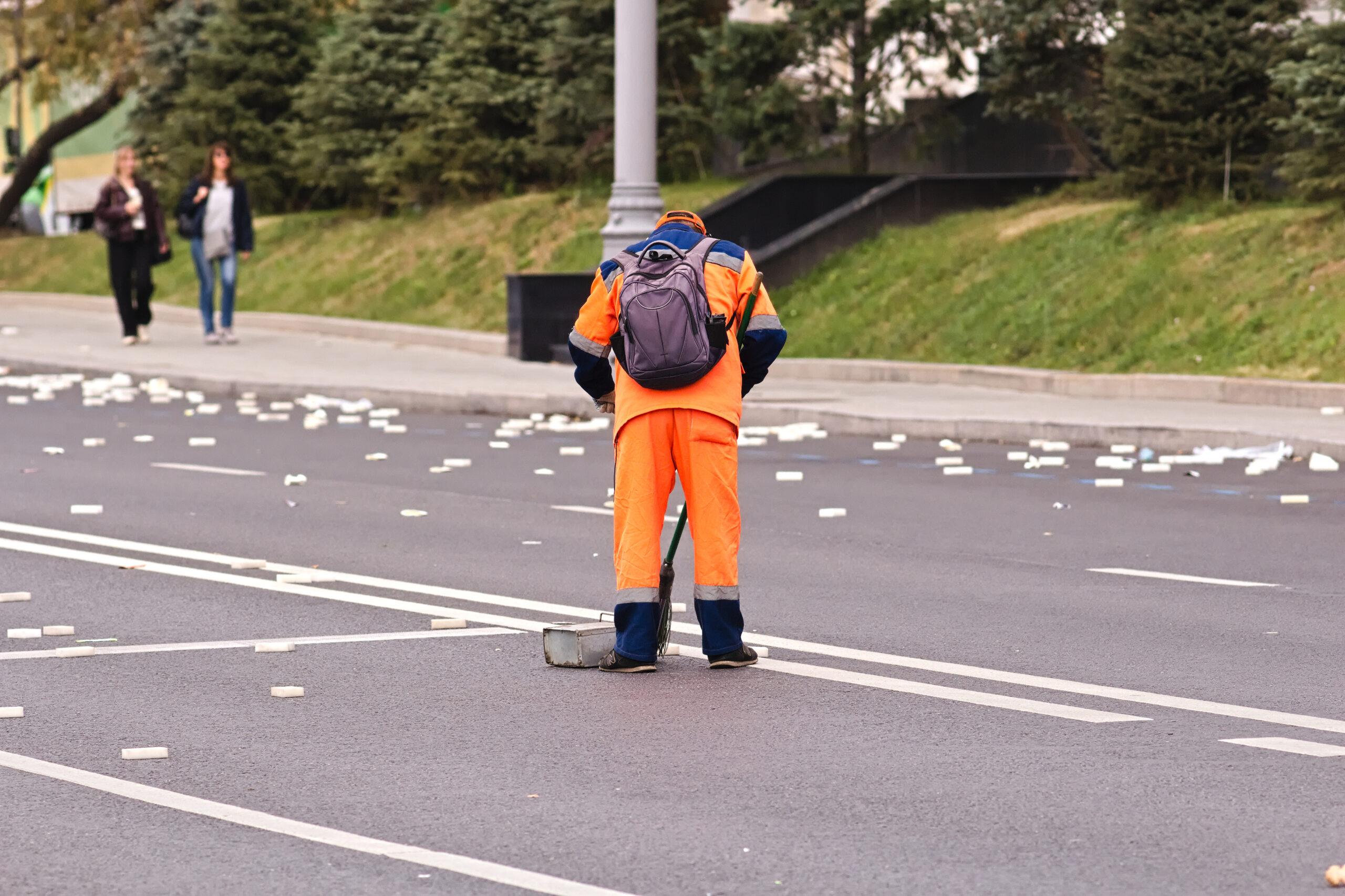 Operatore ecologico con divisa ad alta visibilità che pulisce una strada al mattino