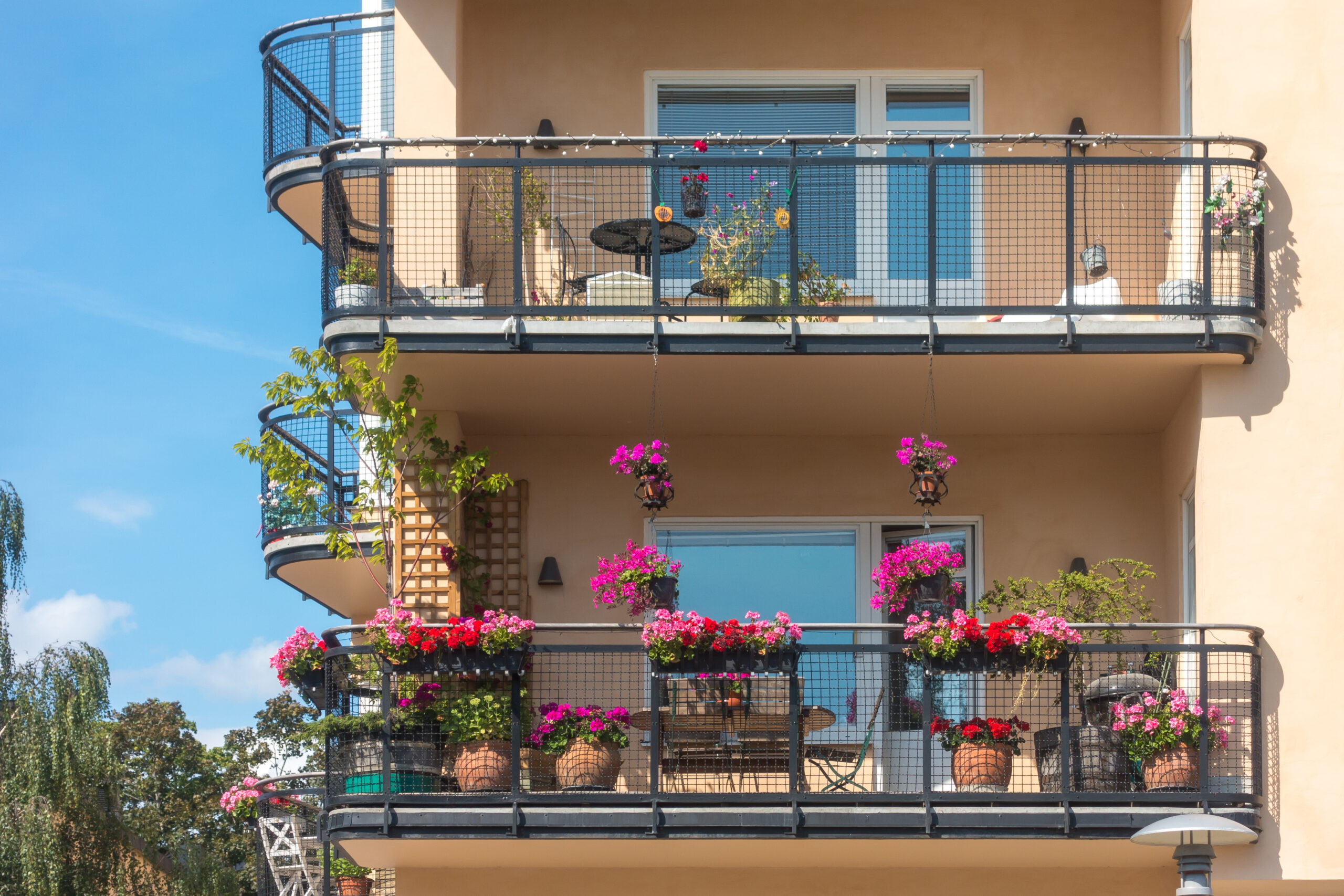 Balcone fiorito con piante in vaso su una facciata colorata, esempio di giardinaggio in spazi piccoli in città