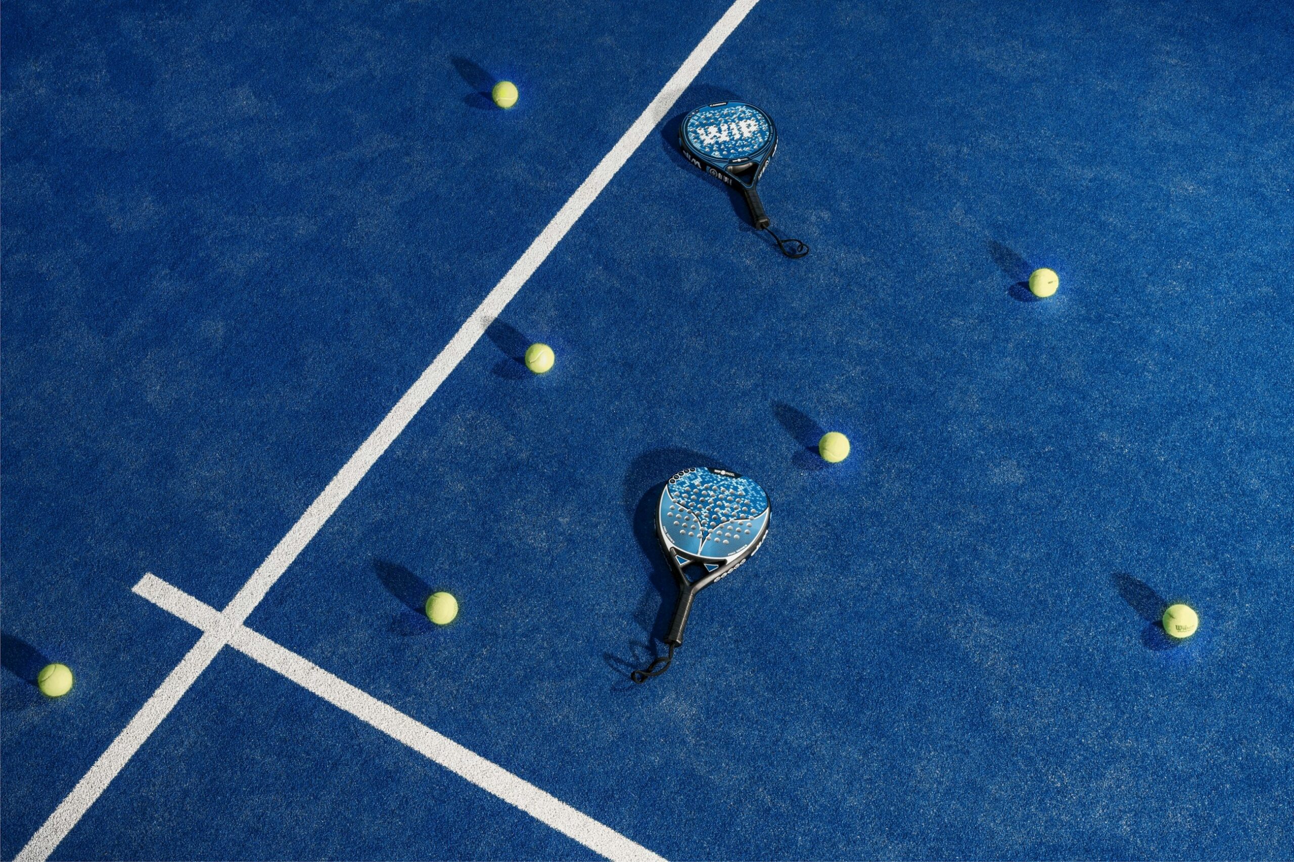 Due racchette da padel e palline su un campo da padel blu