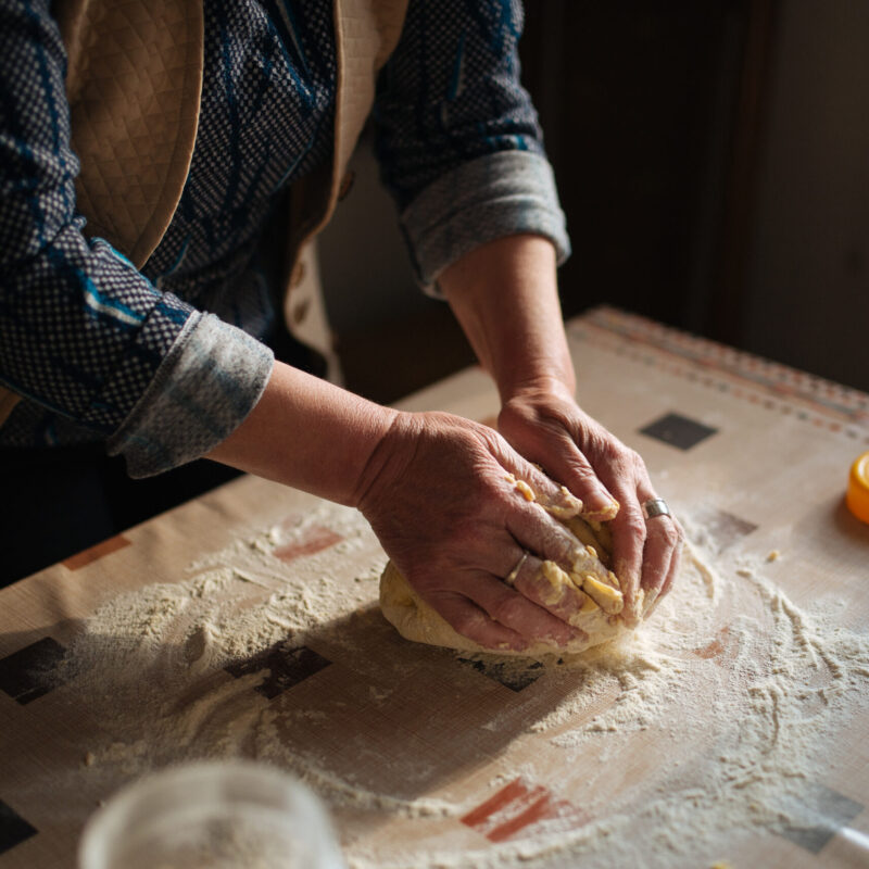 Mani che impastano il pane su un tavolo infarinato