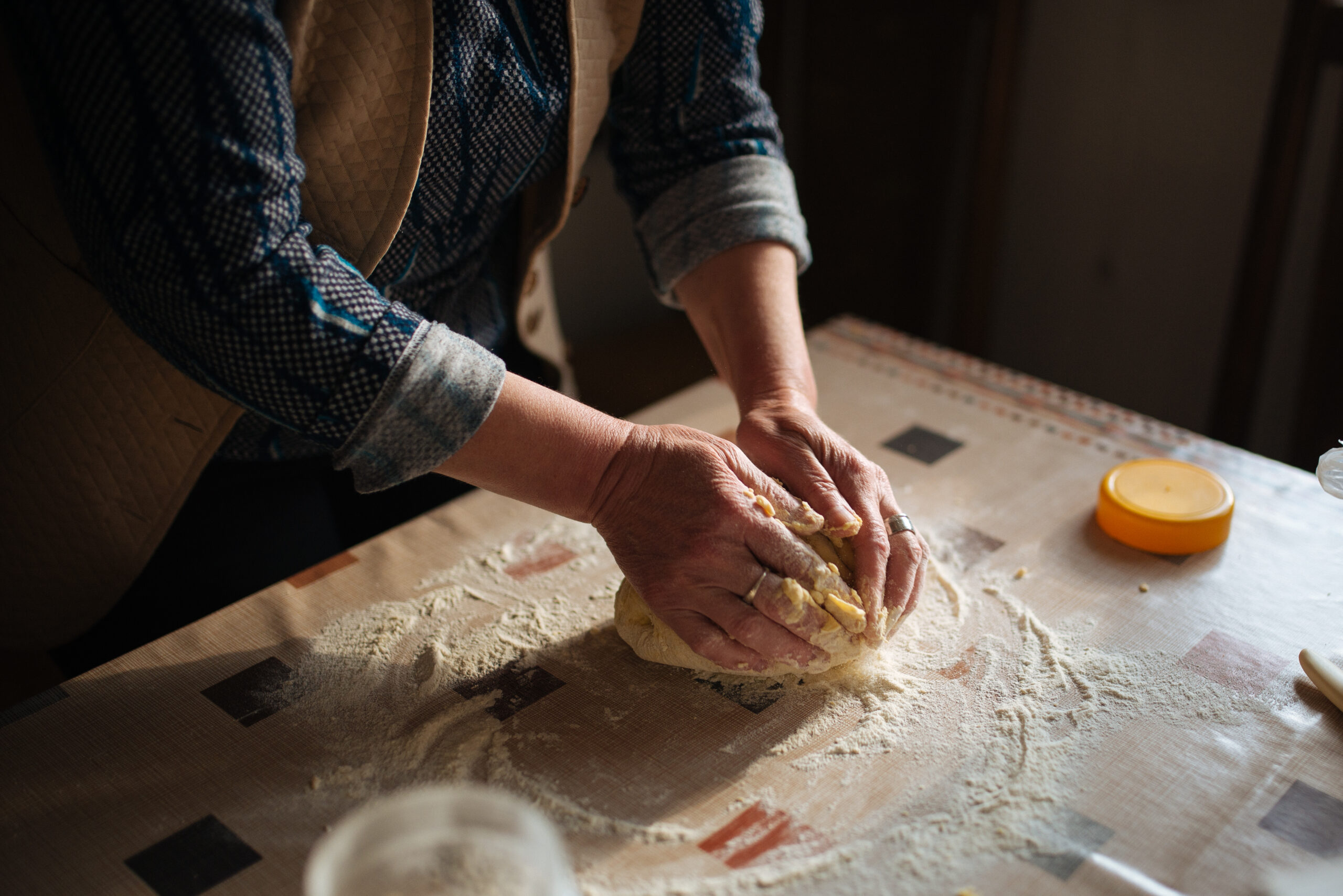 Mani che impastano il pane su un tavolo infarinato