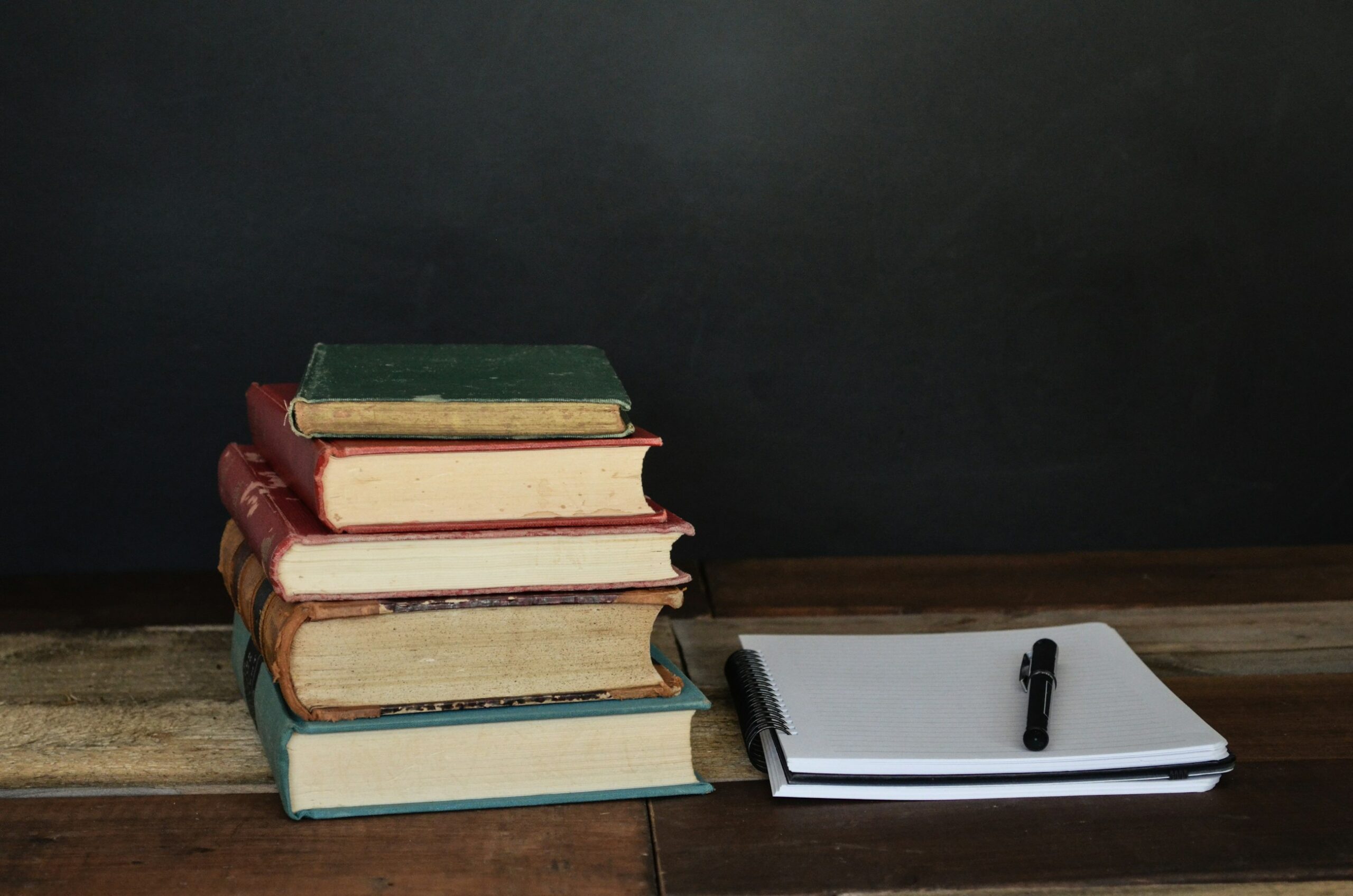 Pila di libri accanto a fogli e penna, ambientazione per lo studio serale in preparazione a un concorso pubblico