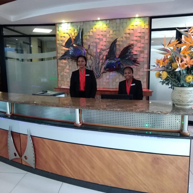 Due receptionist sorridenti alla reception di un hotel, in uniforme