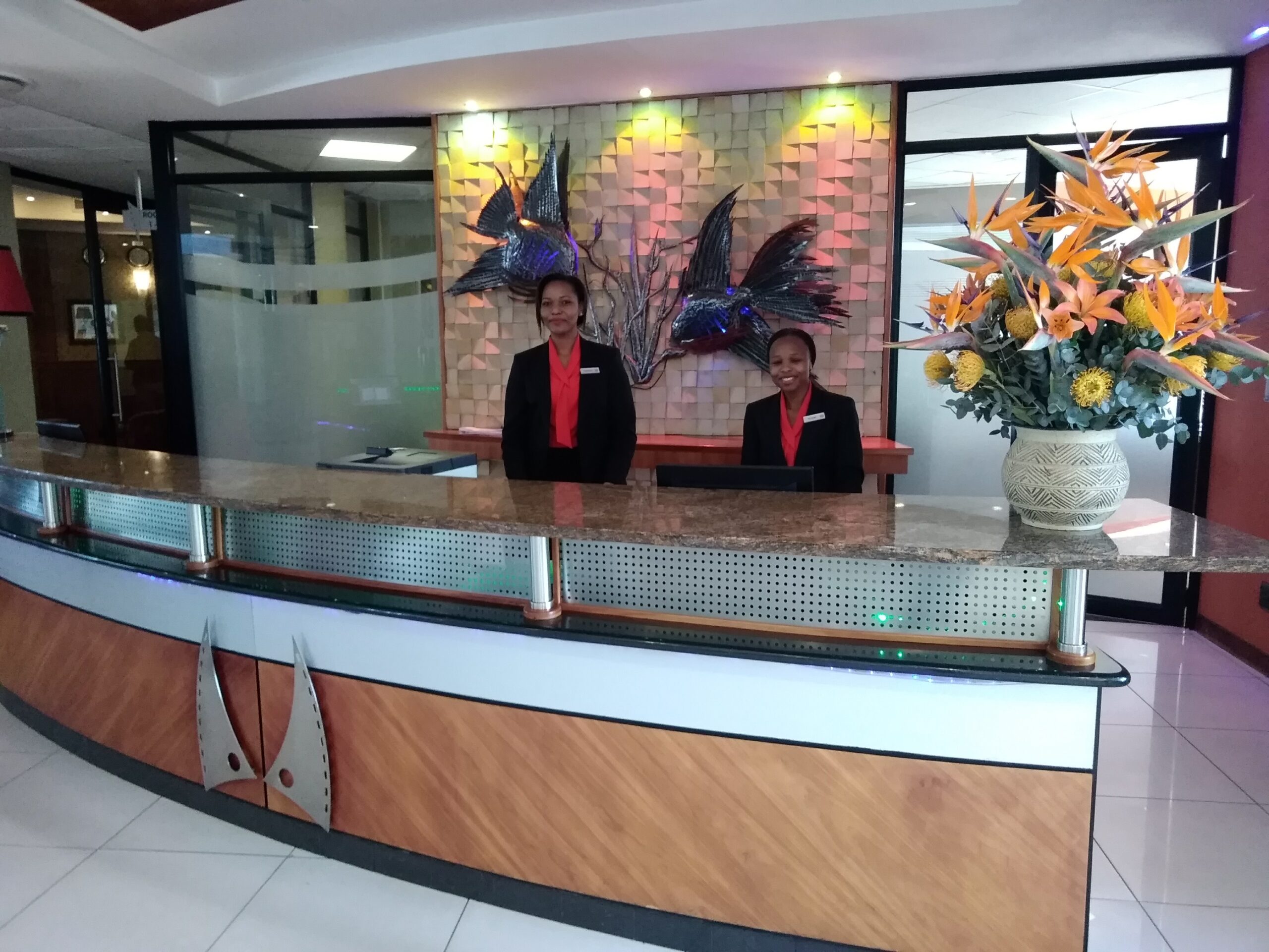 Due receptionist sorridenti alla reception di un hotel, in uniforme