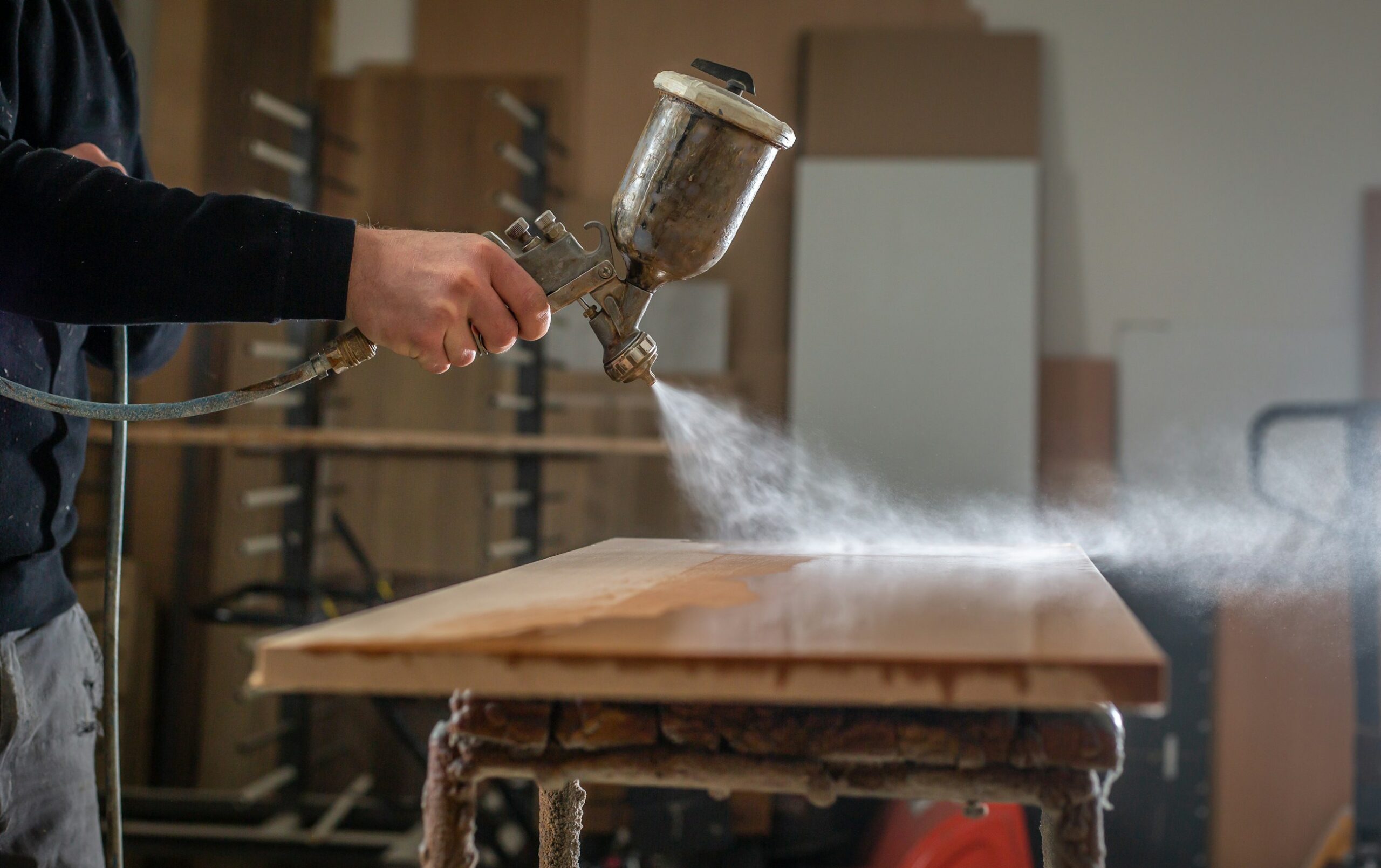 Persona che usa una smerigliatrice per carteggiare un tavolo di legno durante un restauro di mobili
