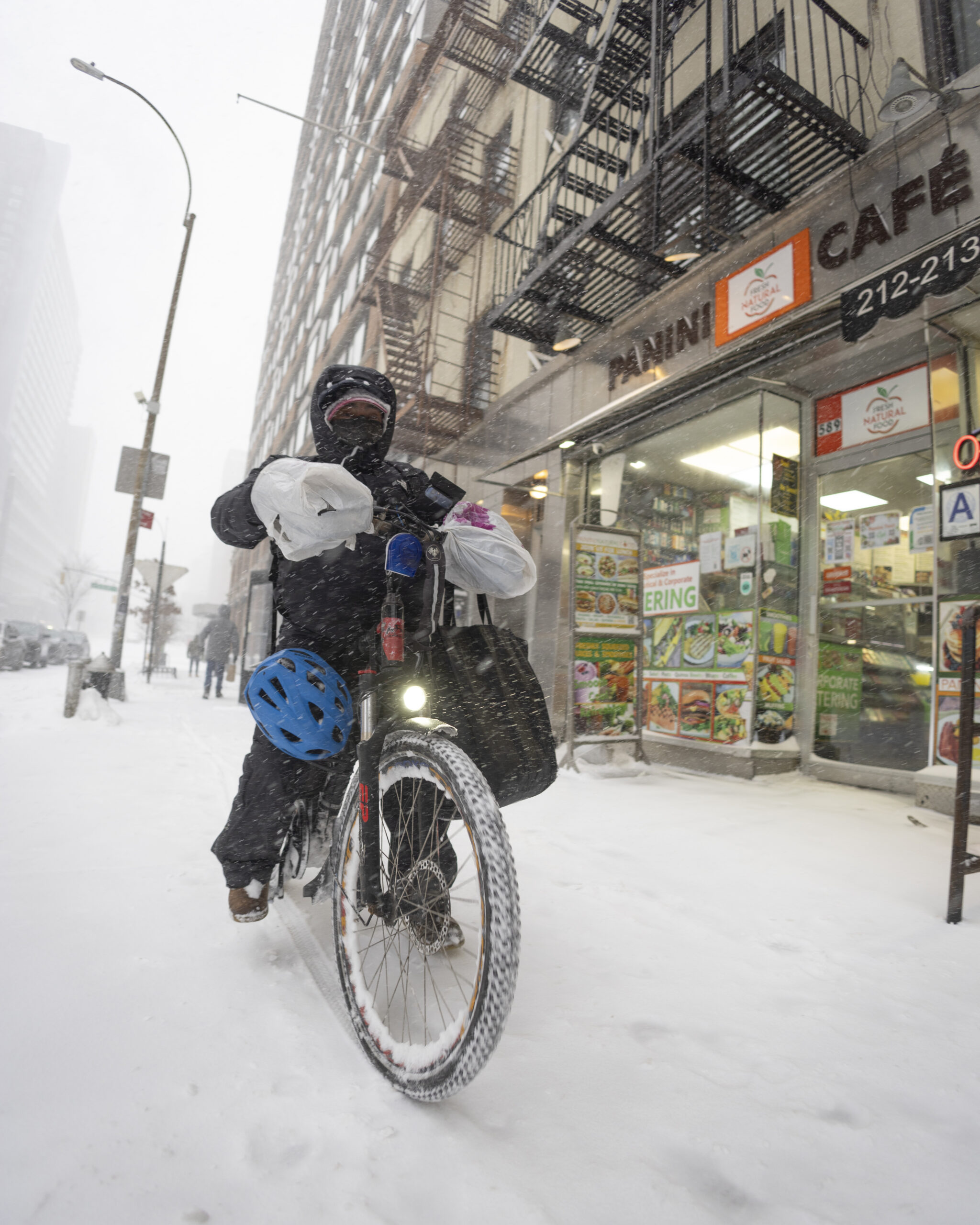 Rider in bicicletta consegna cibo a domicilio durante una tempesta di neve in città
