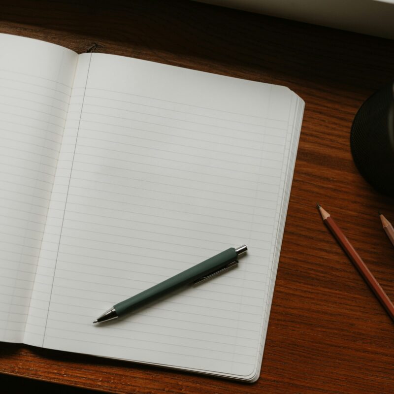 Quaderno e penne su una scrivania di legno