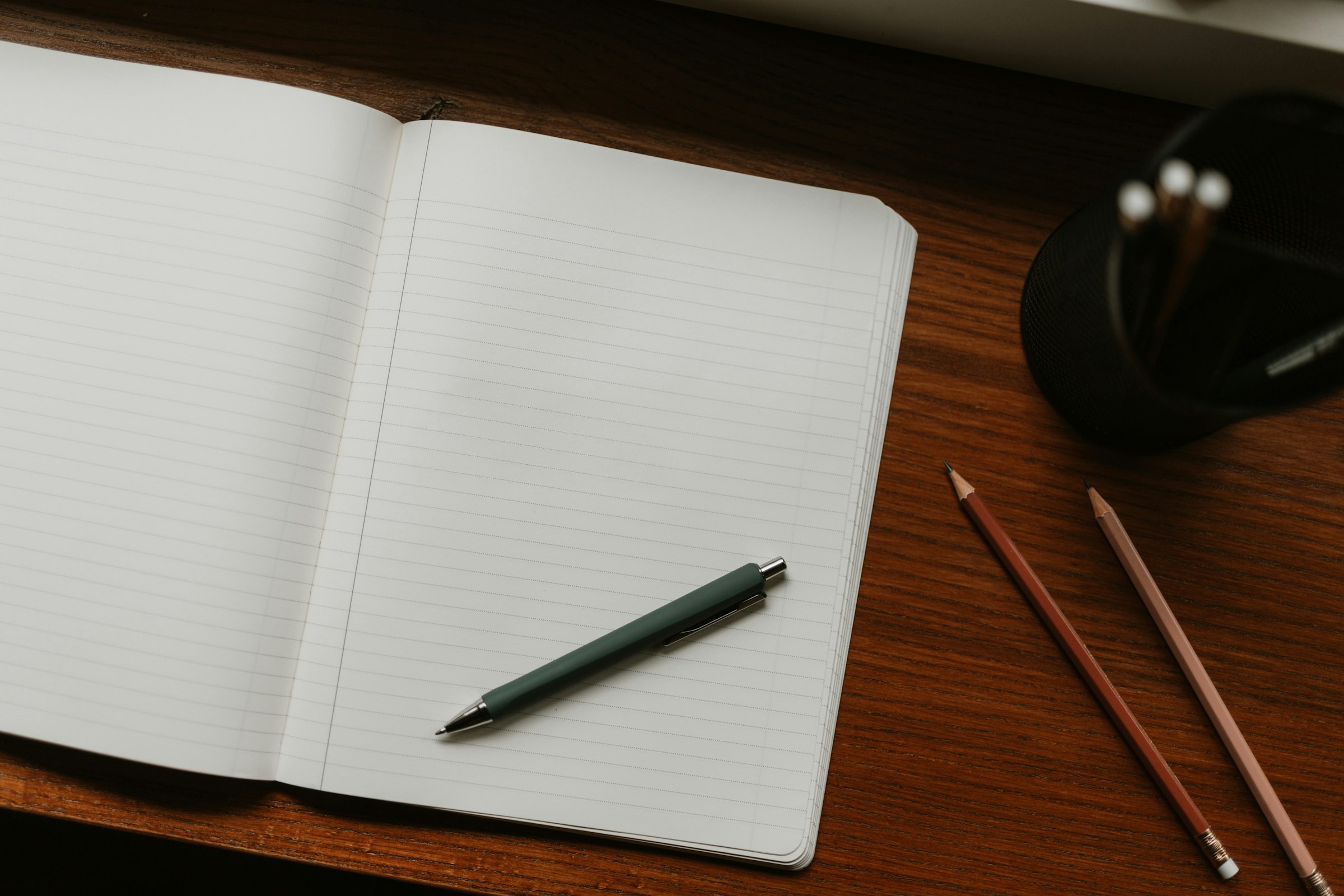 Quaderno e penne su una scrivania di legno
