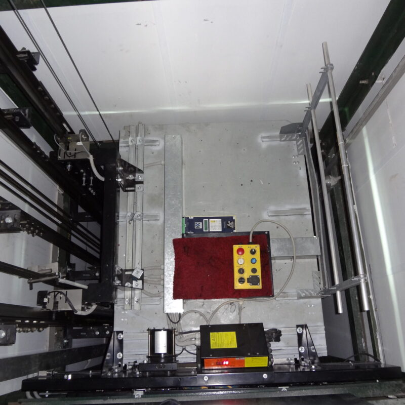 Sala macchine di un ascensore con motore, argano e quadro di comando durante manutenzione