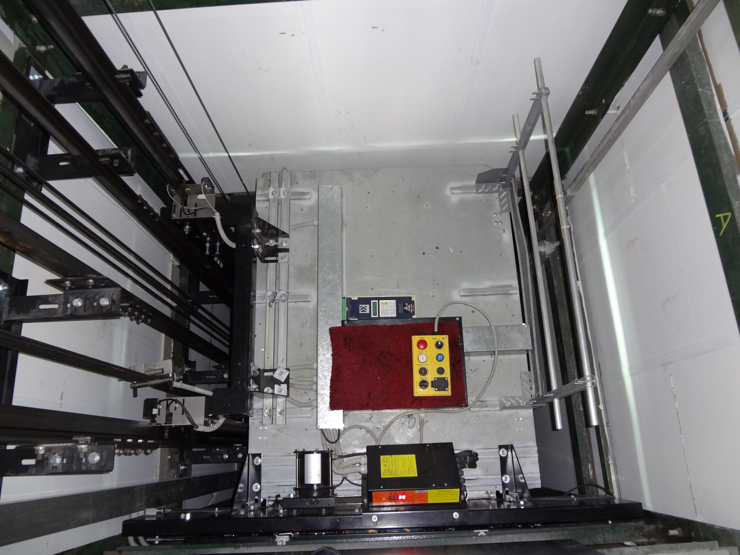 Sala macchine di un ascensore con motore, argano e quadro di comando durante manutenzione